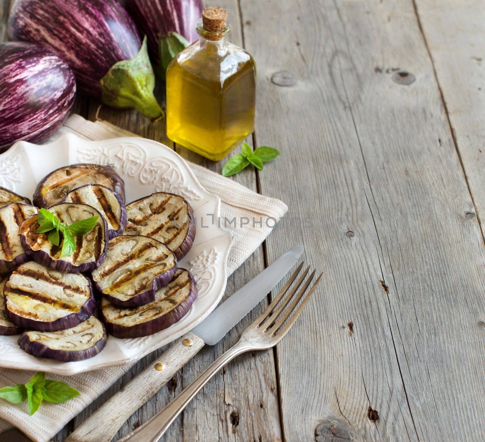 Grilled eggplants seasoned with olive oil on a wooden table