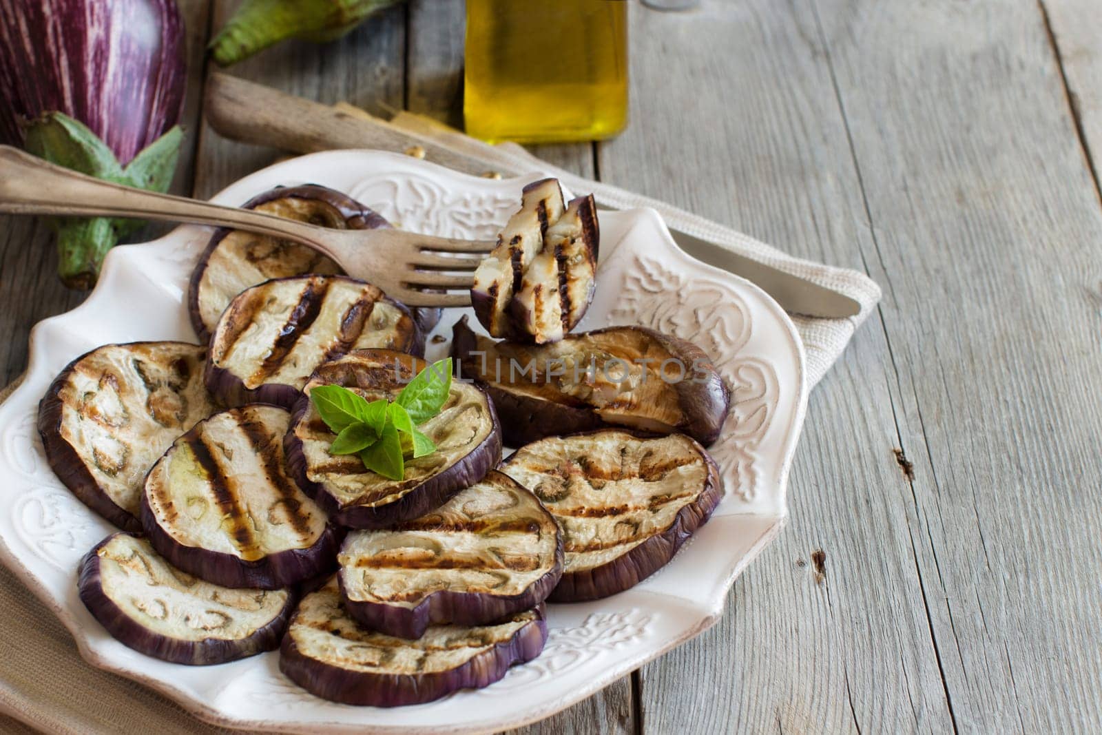 Grilled eggplants seasoned with olive oil on a wooden table