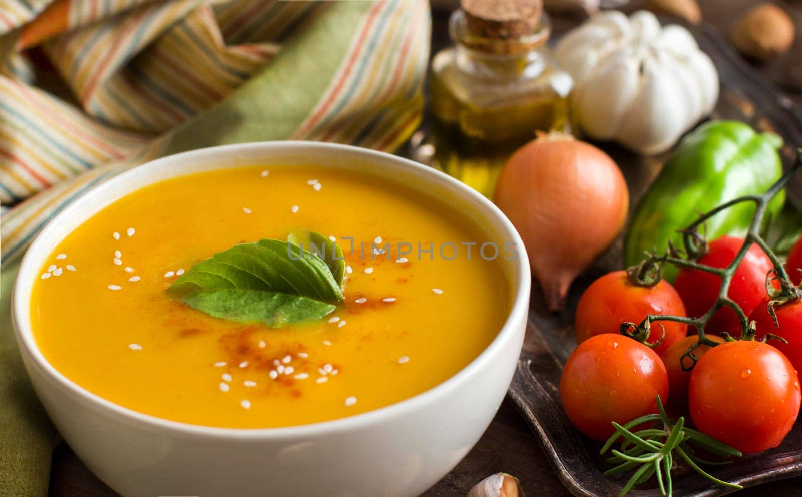 Fresh pumpkin soup with a spoon and vegetables on a wooden table