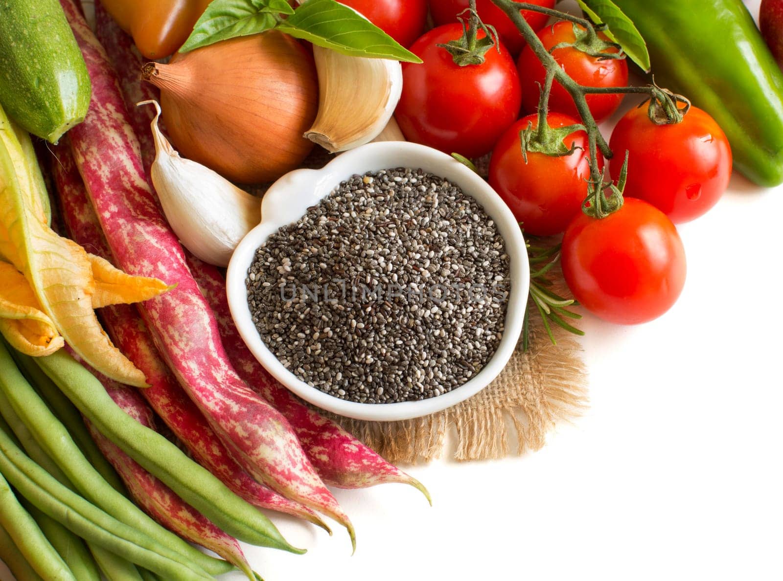 Raw chia seeds in bowl and vegetables isolated on white