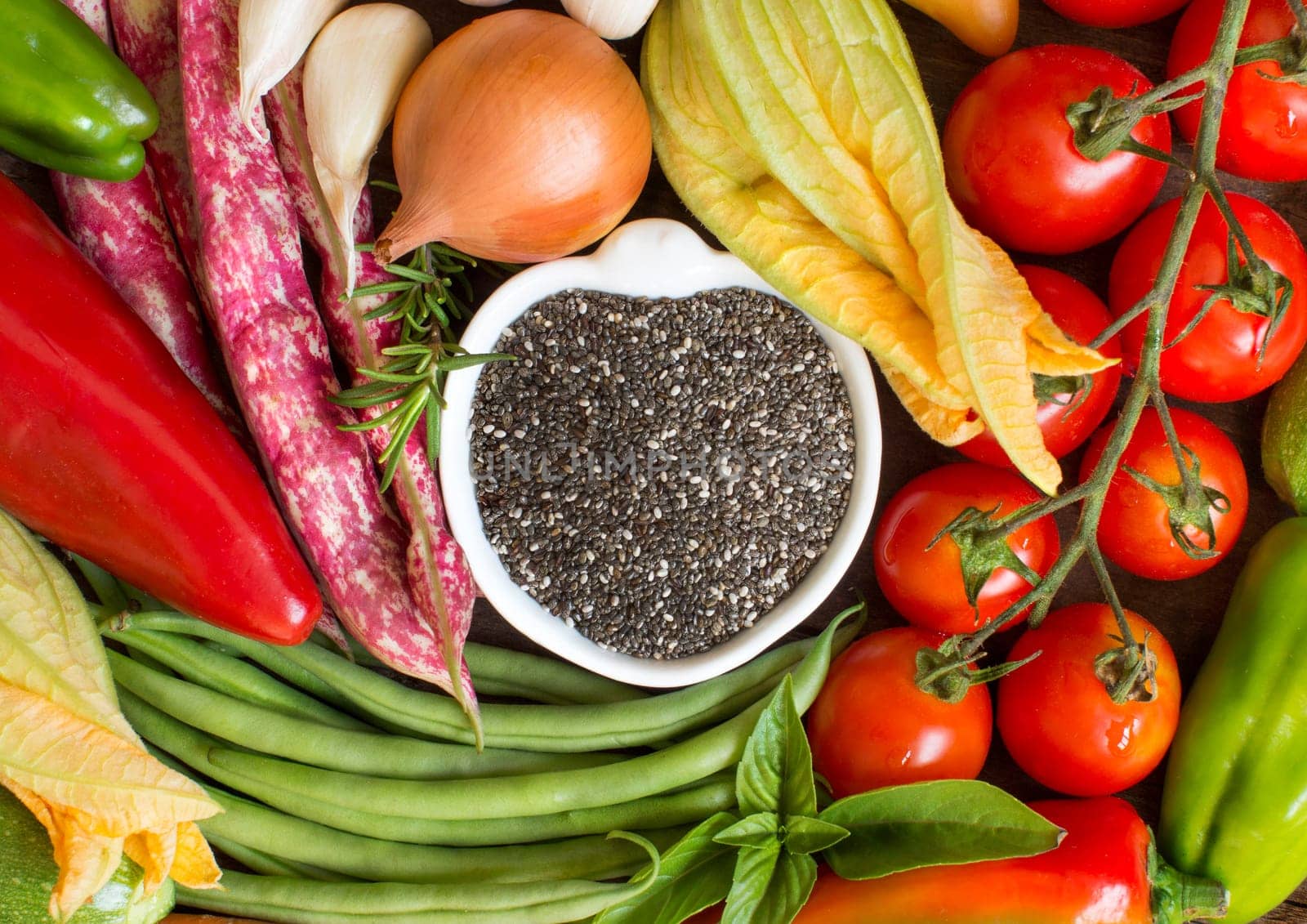 Raw chia seeds in bowl and vegetables top view