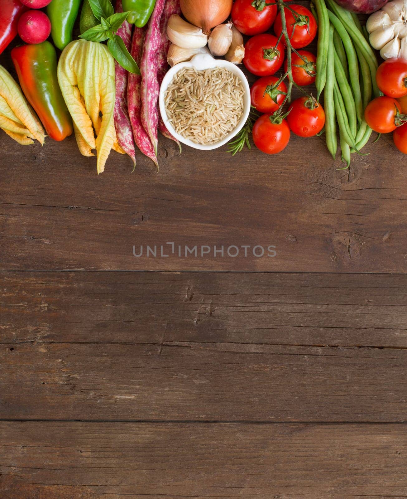 Unpolished raw rice and vegetables on a wooden background
