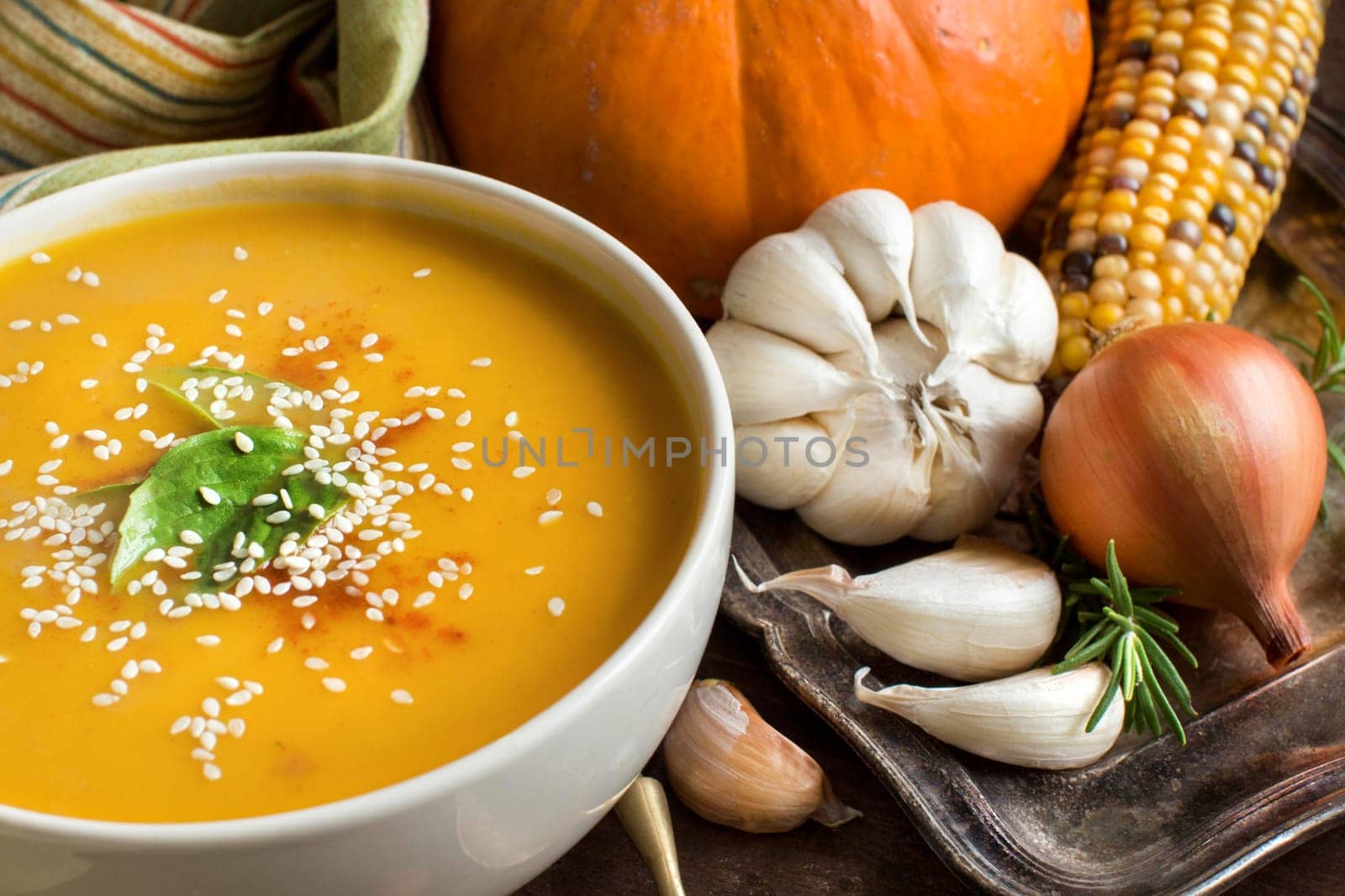 Fresh pumpkin soup with a spoon and vegetables on a wooden table