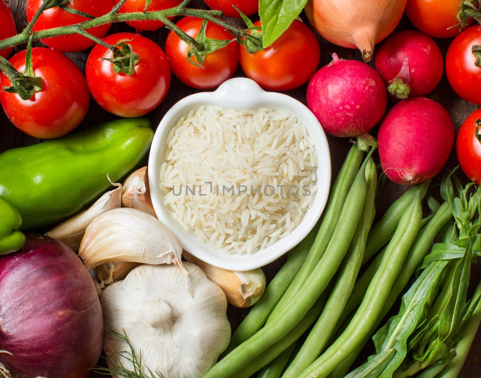 Basmati rice in bowl and fresh vegetables and herbs
