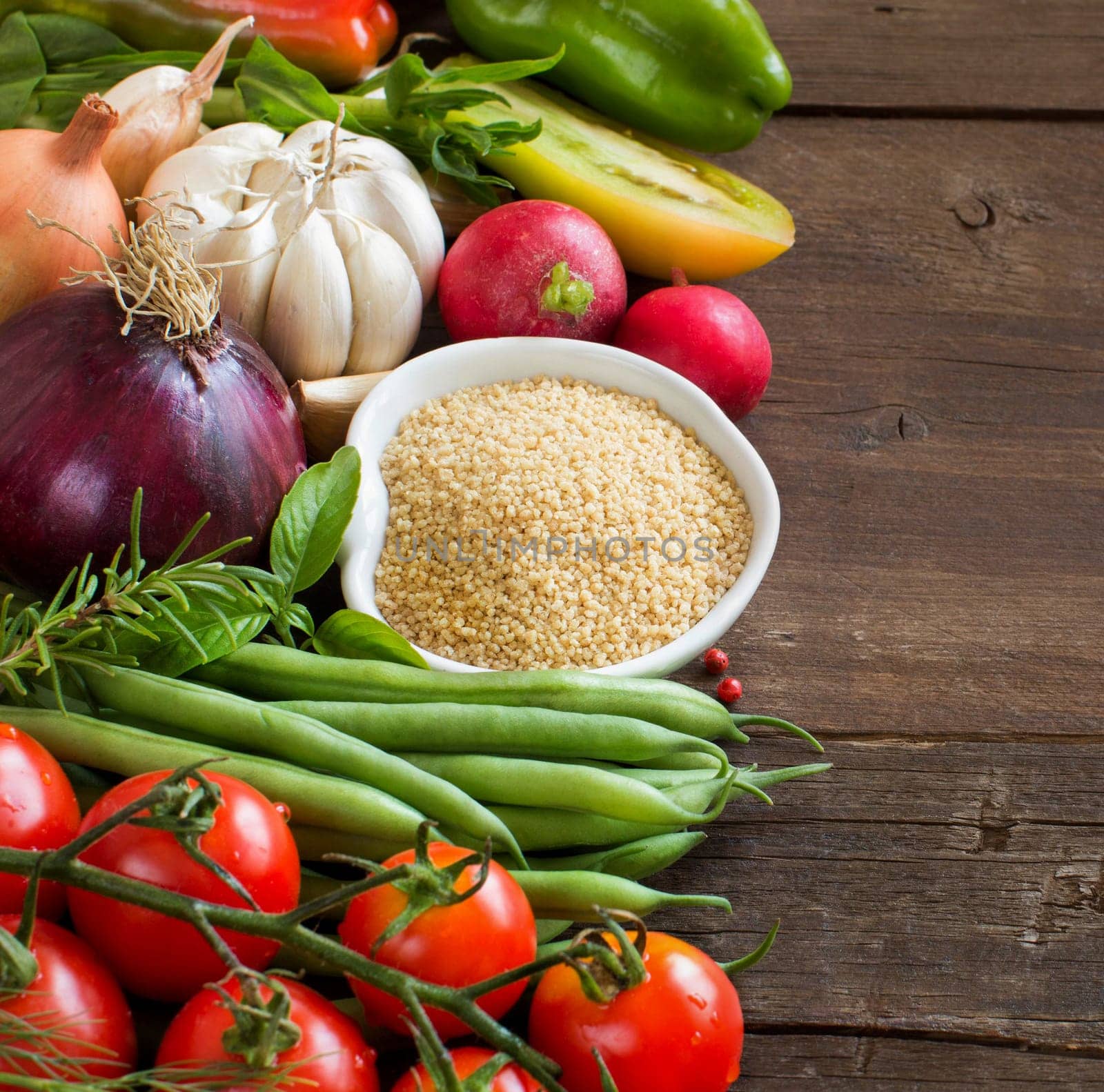 CousCous in a bowl and fresh vegetables on wood
