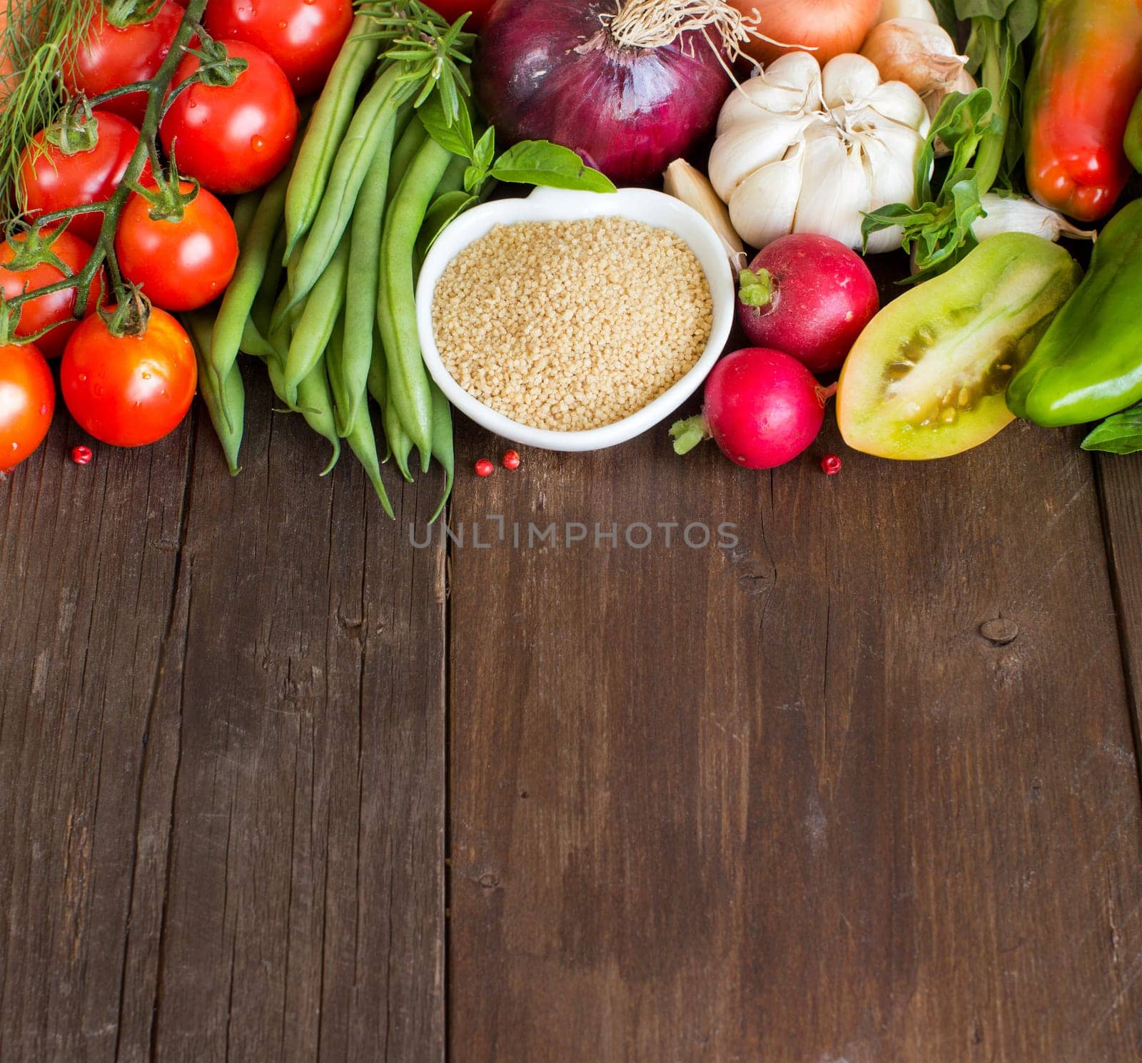 CousCous in a bowl and fresh vegetables on wood