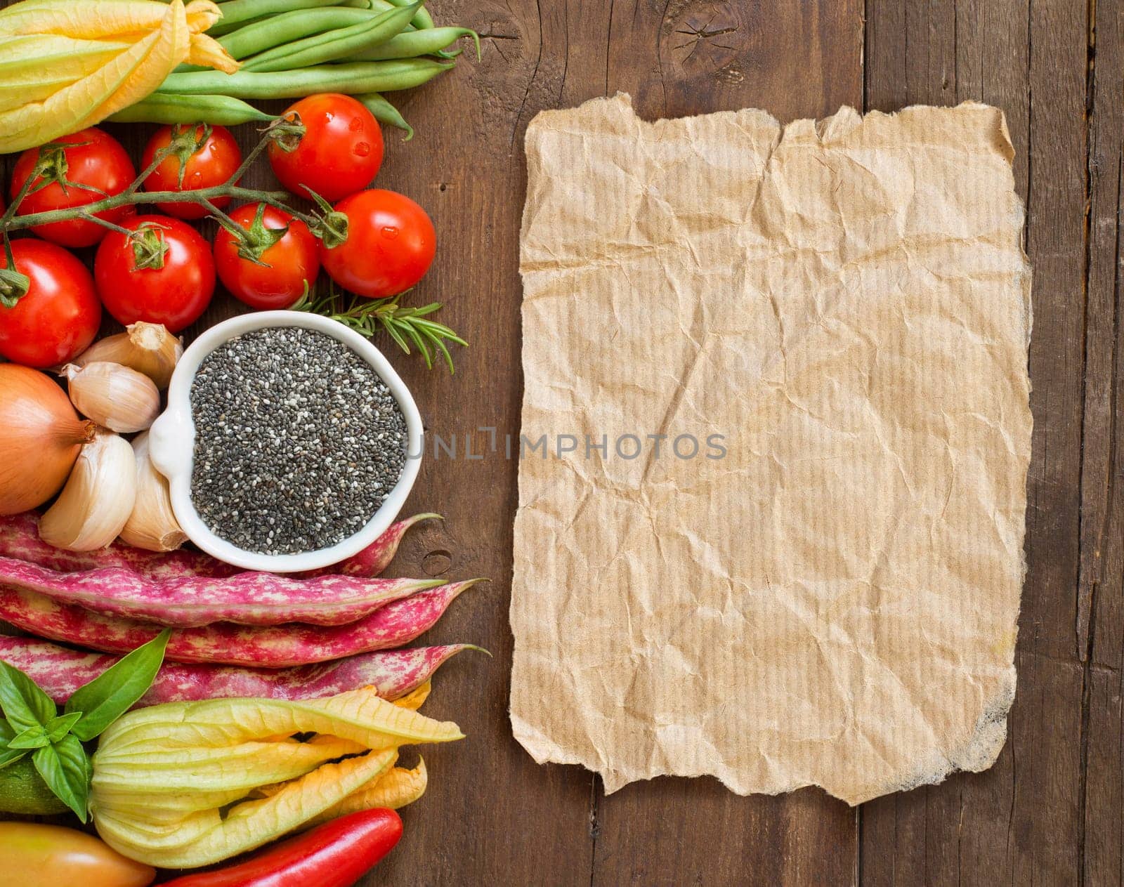 Raw chia seeds in a bowl and fresh vegetables top view