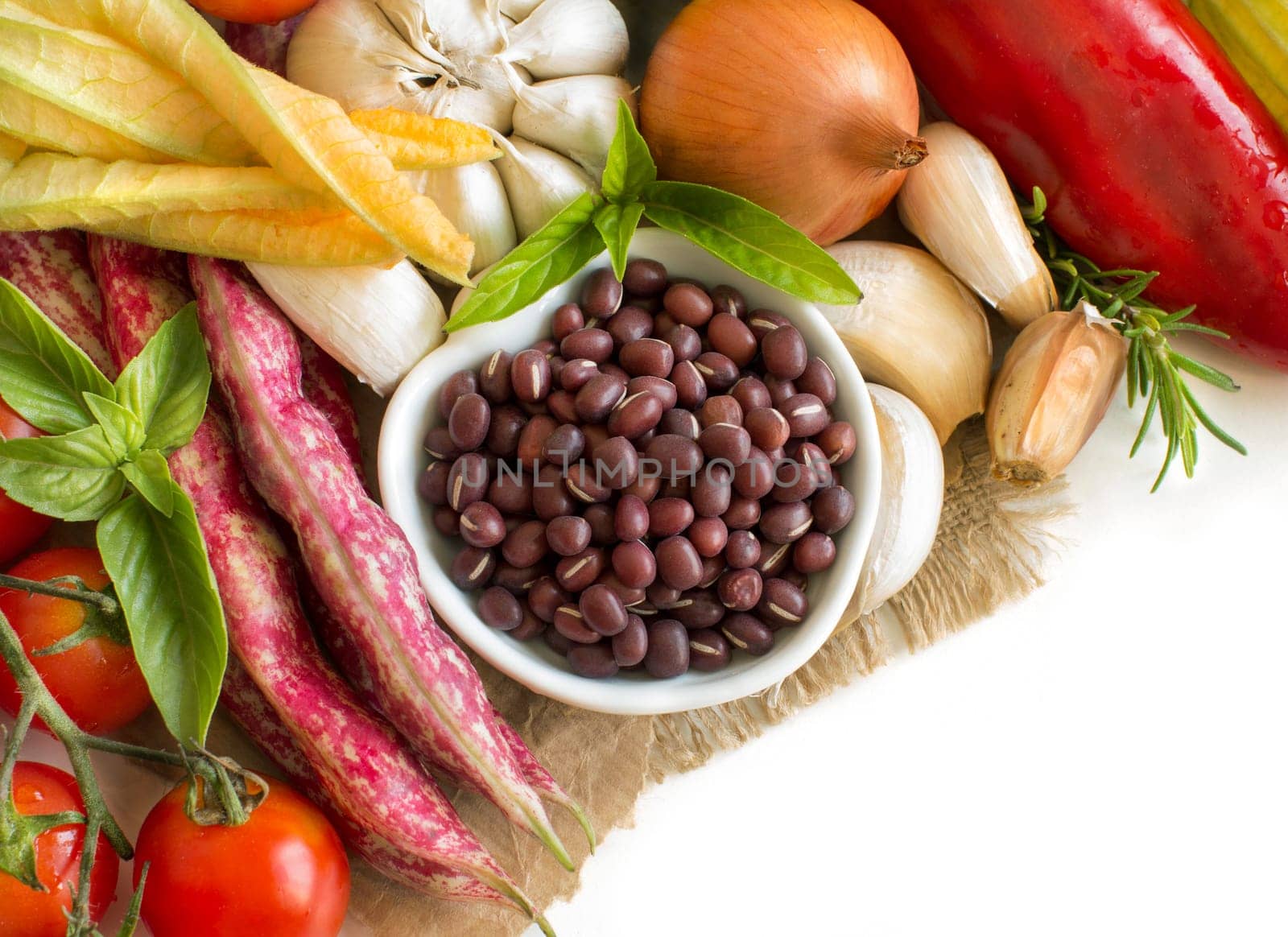 Raw azuki beans in a bowl and fresh vegetables isolated on white