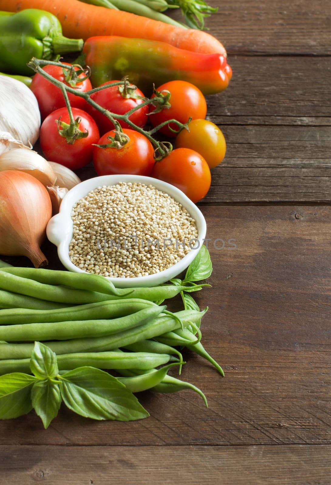 Quinoa in a bowl and fresh vegetables on a wooden table