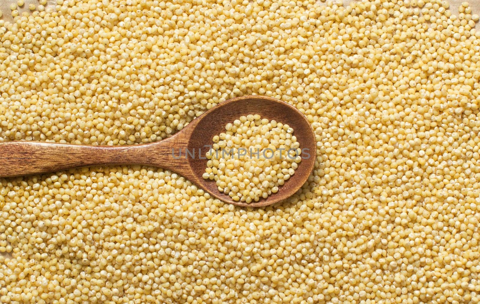 Raw yellow millet with a spoon close up