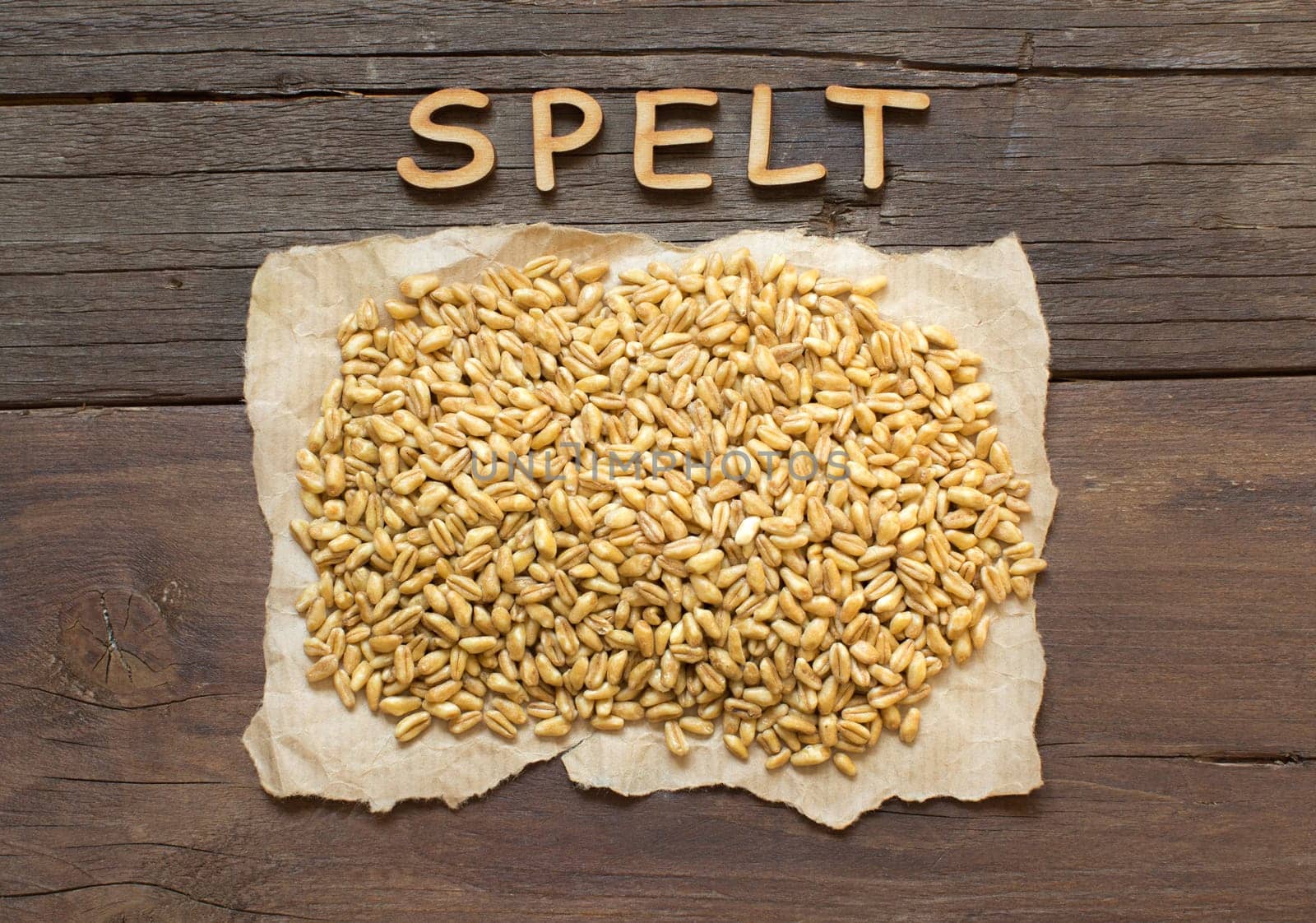 Raw Organic spelt grain with wooden word on a wooden background