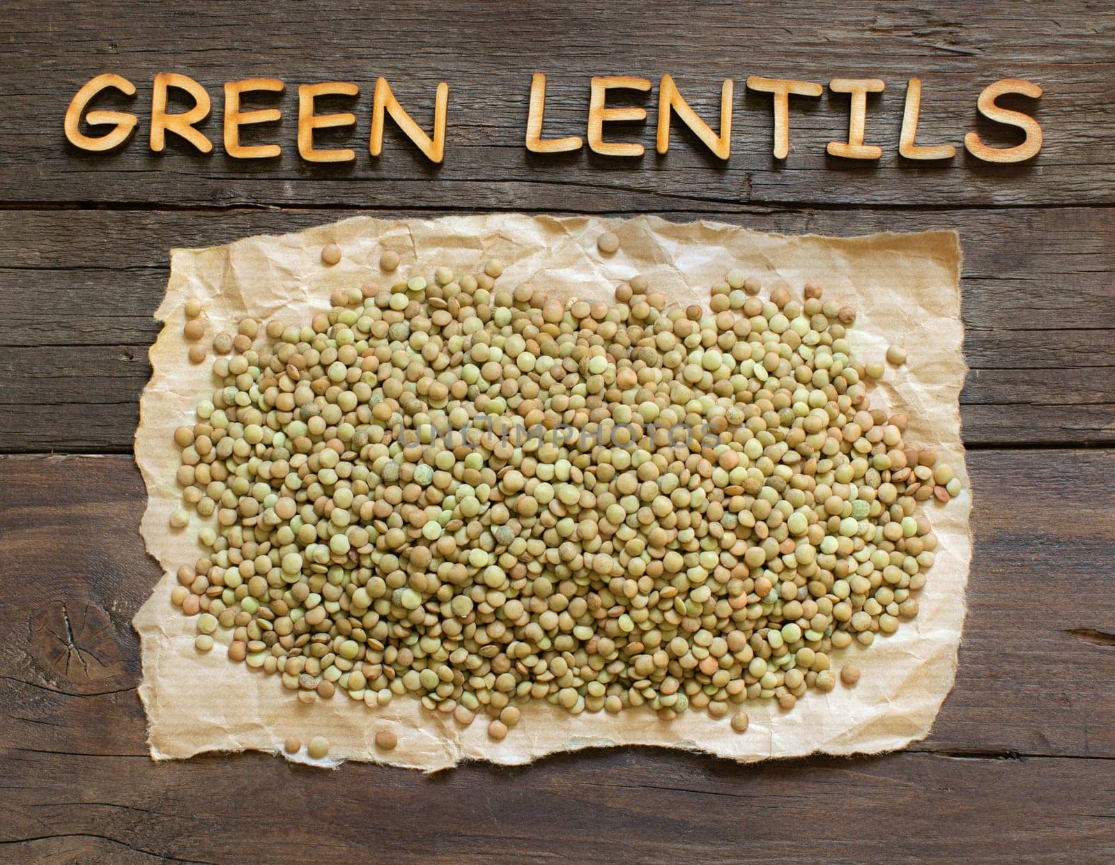 Green lentils on the dark table with wooden word Green Lentil