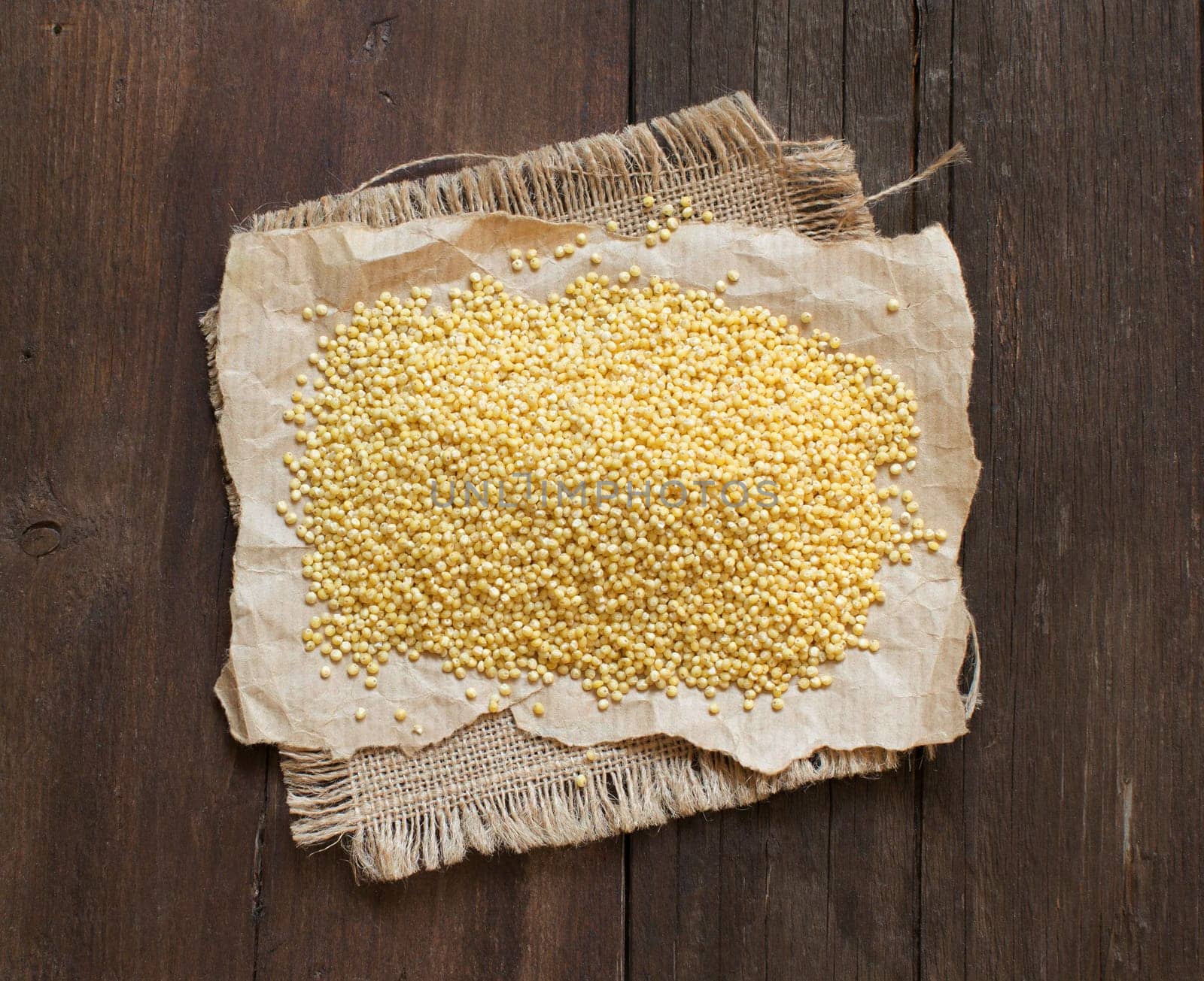 Raw millet on craft paper on dark wooden table