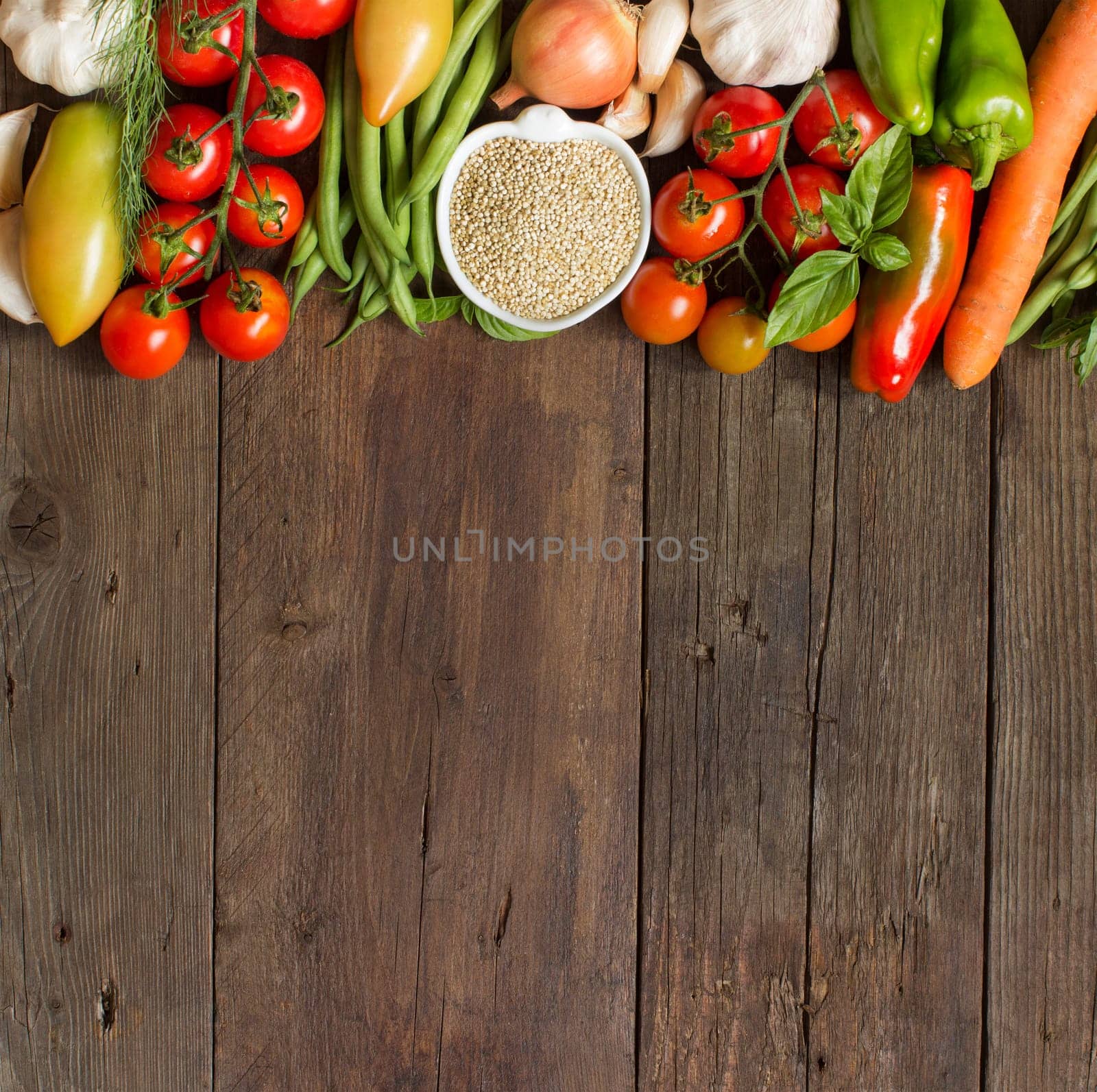 Quinoa in a bowl and fresh vegetables on a wooden table