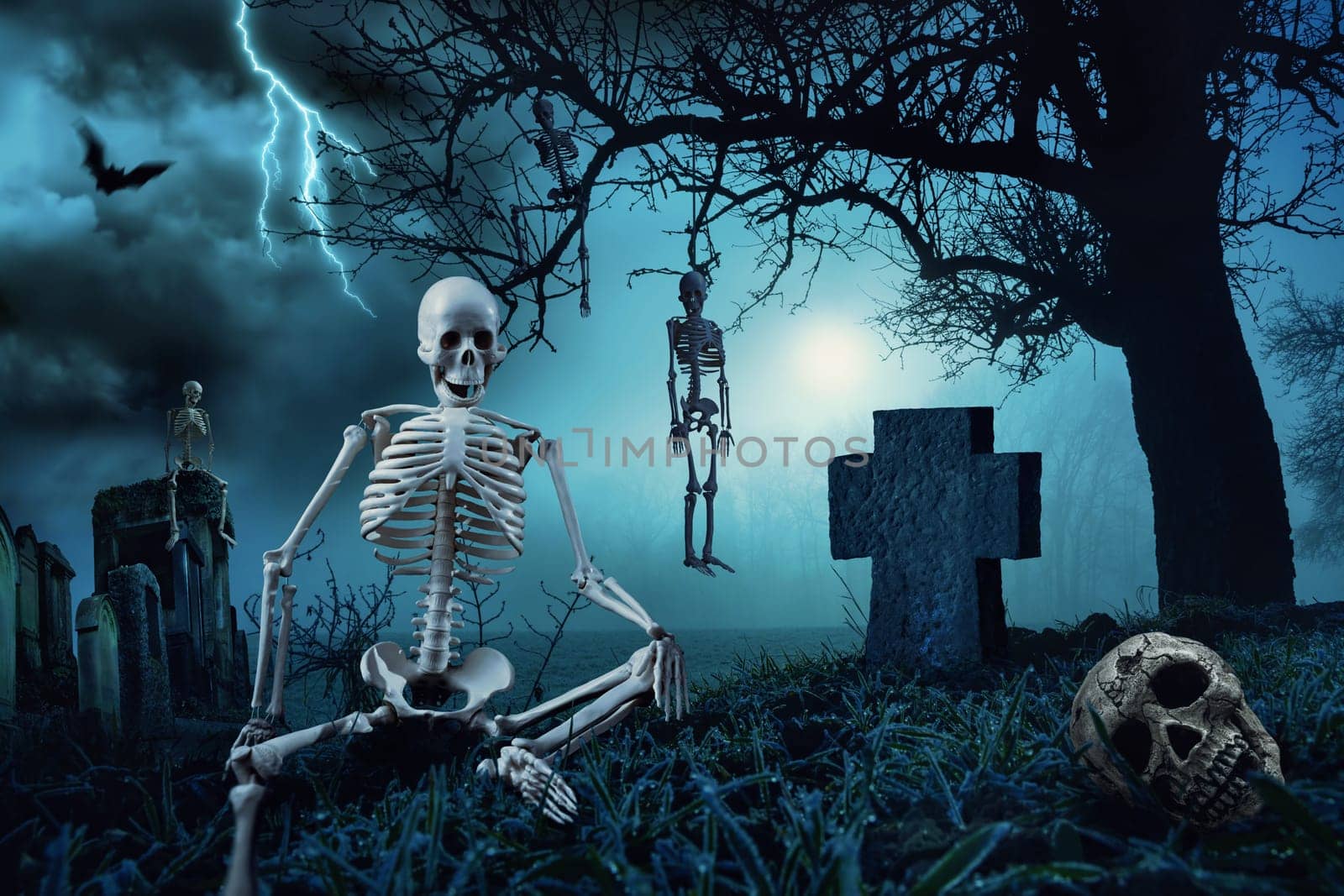 Nighttime Halloween scene with skeletons at a cemetery and the silhouette of a dead tree in the blue moonlight