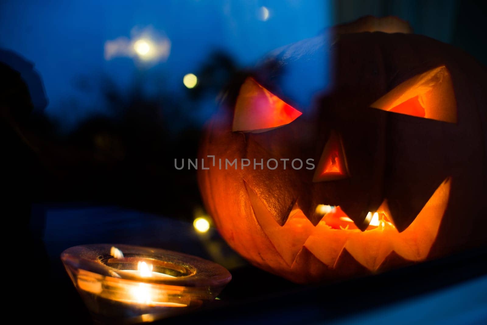 halloween pupkin symbol behind the home window with light at night reflectons
