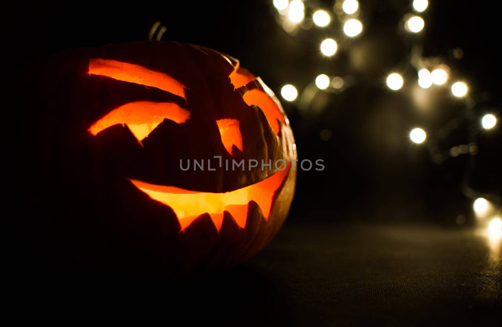 carved face of pumpkin glowing on halloween on bokeh light background