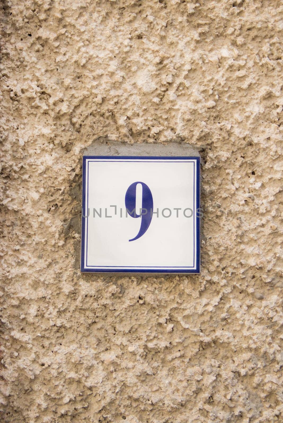 Ceramic number nine on the grey stone wall