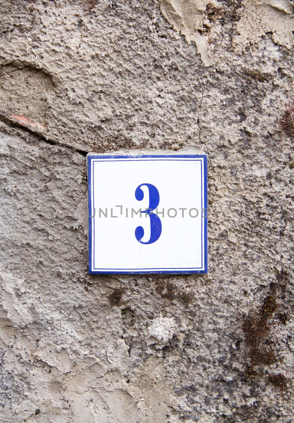 Ceramic number three on the grey stone wall