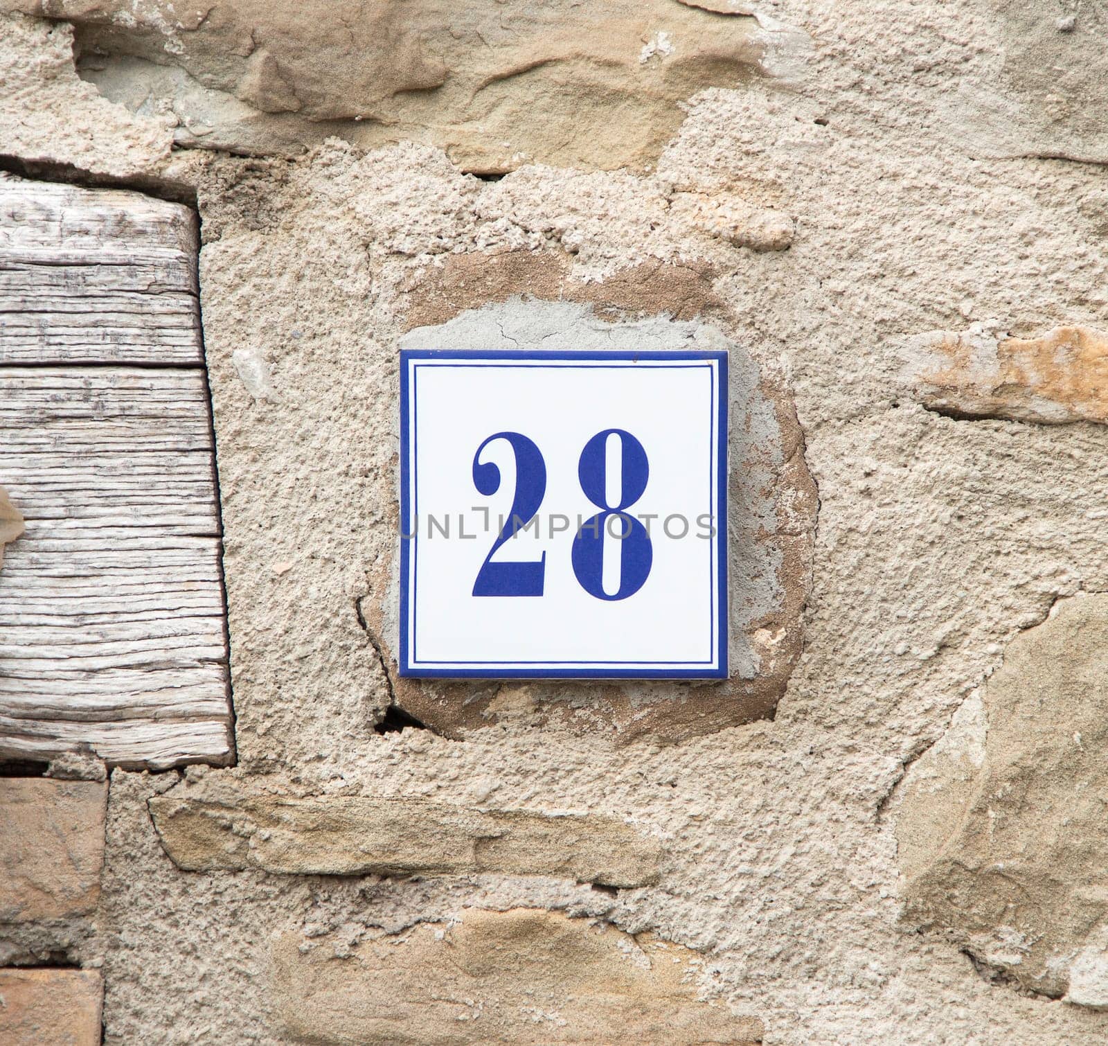 Ceramic number twenty eight on the grey stone wall