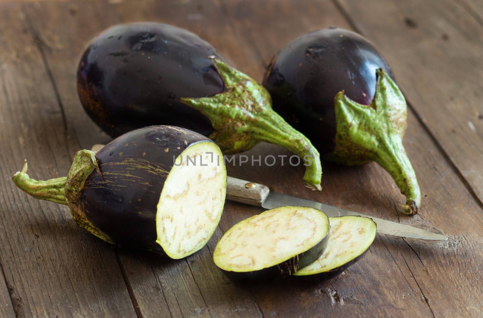 Fresh Raw eggplants with knife on the wood background