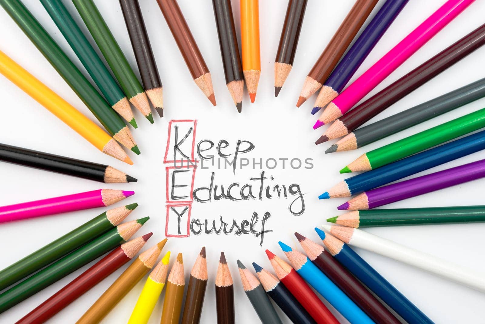 Colouring pencils in circle arrangement with message KEY Keep Educating Yourself, education concept