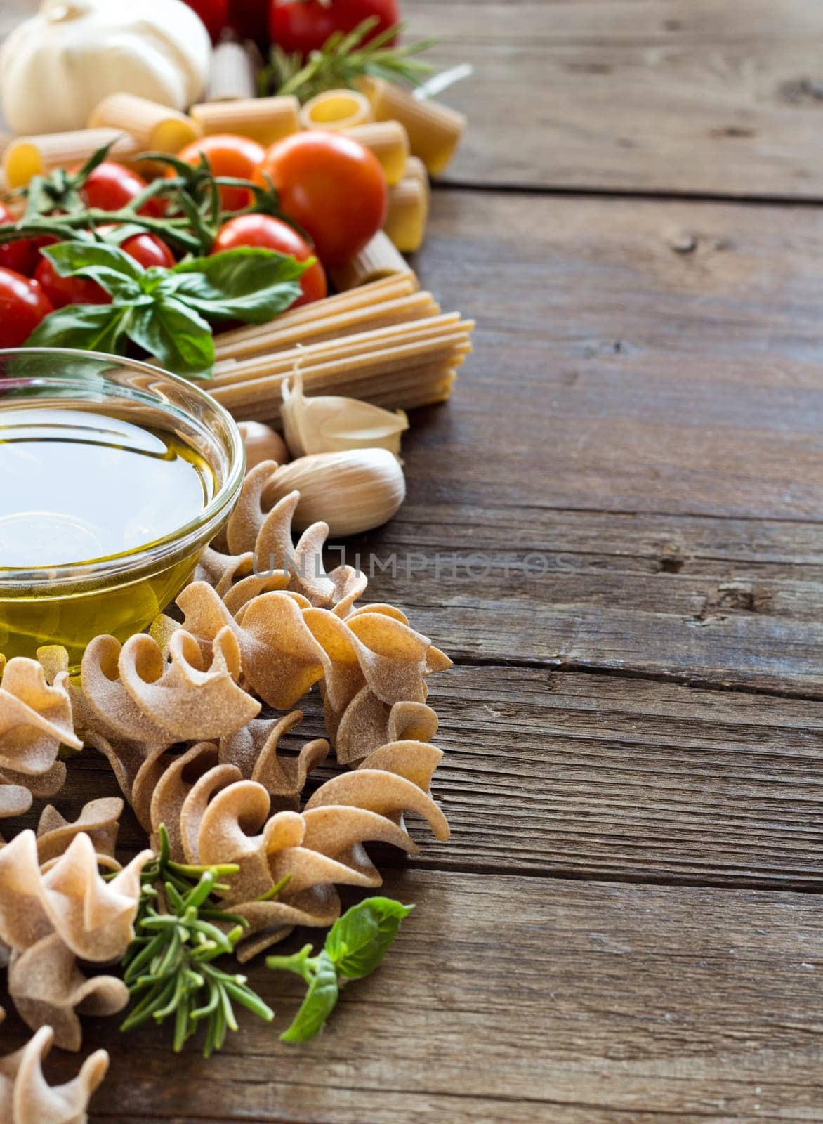Olive oil, pasta, garlic and tomatoes on the wooden table