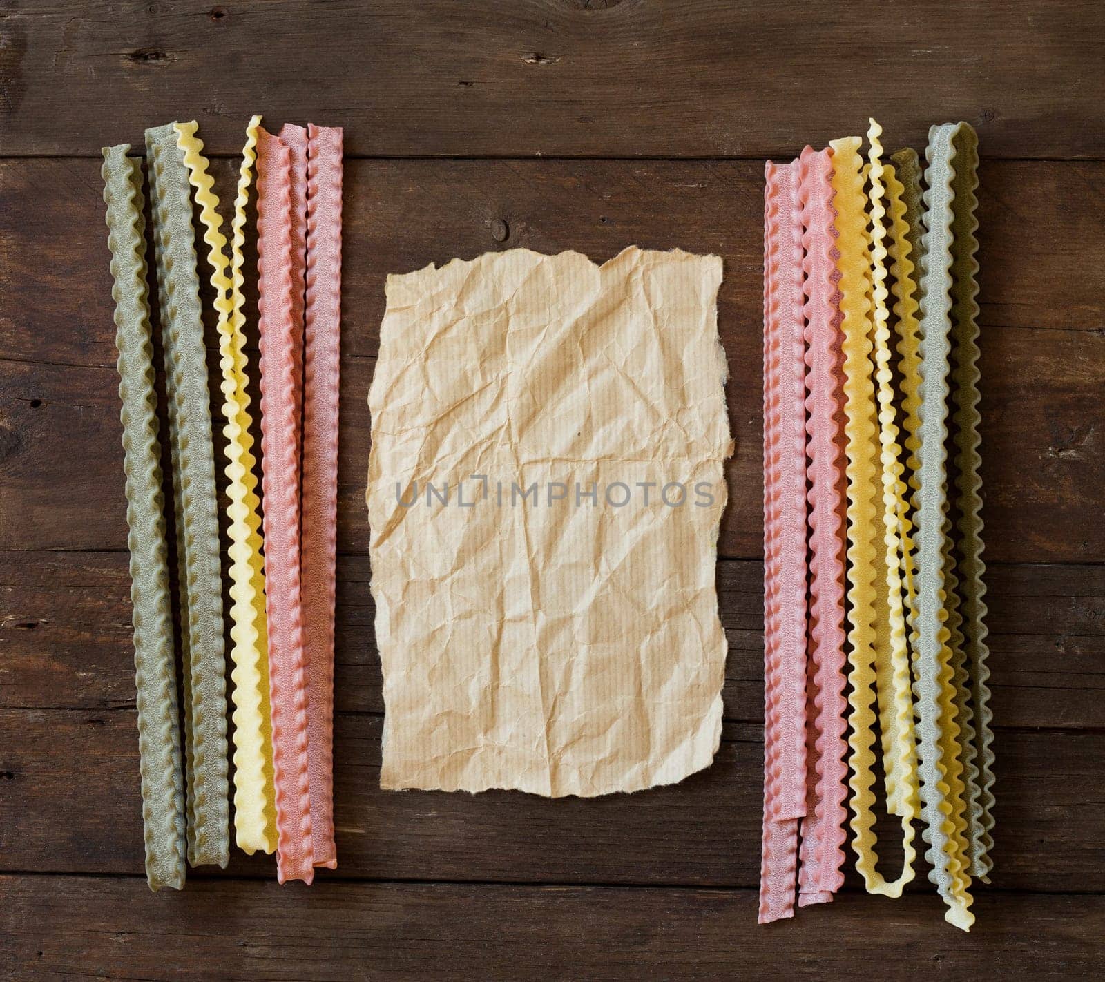 Tricolor mafalde pasta and paper on the old wooded table