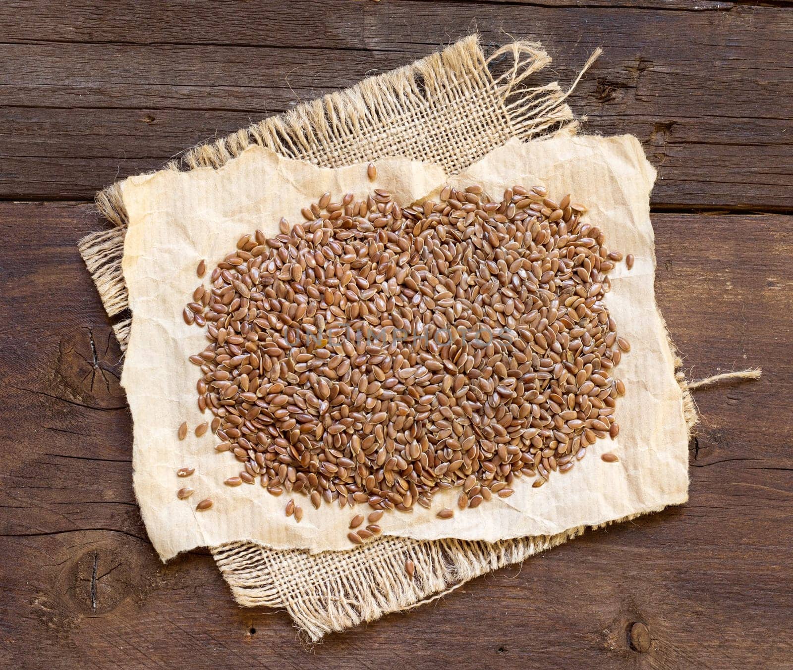 Pile of flax seeds on a wooden background
