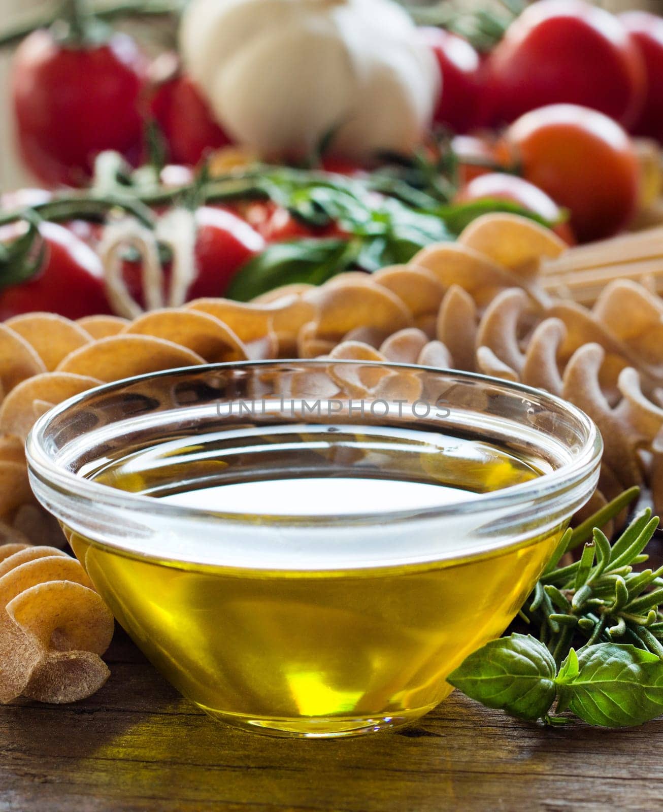 Olive oil, pasta, garlic and tomatoes on the wooden table