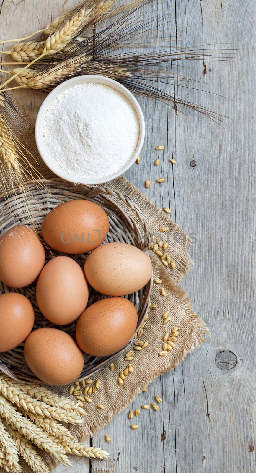 Chicken eggs, wheat and flour on the old wood