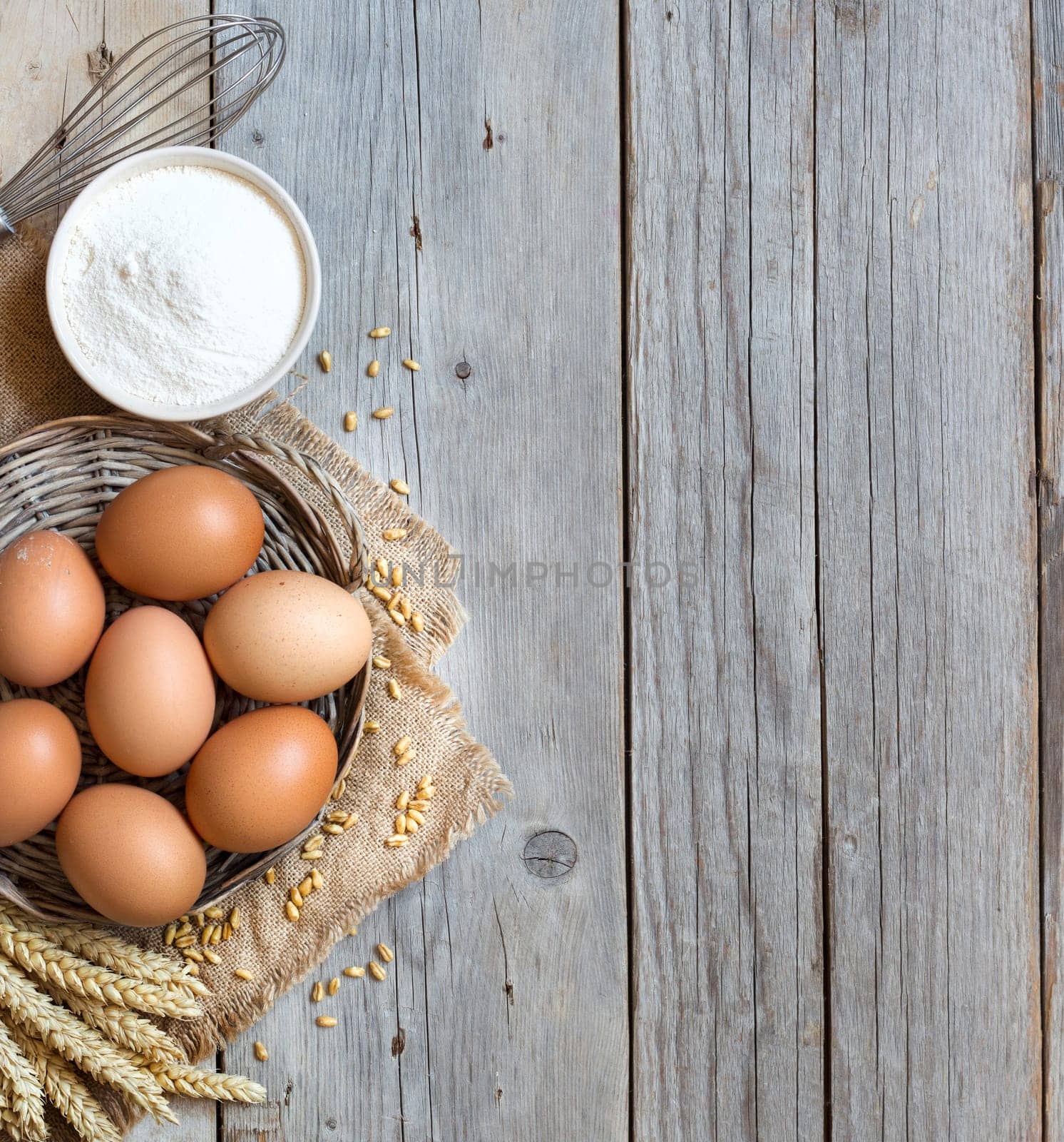 Chicken eggs, whisk, wheat and flour on the old wood