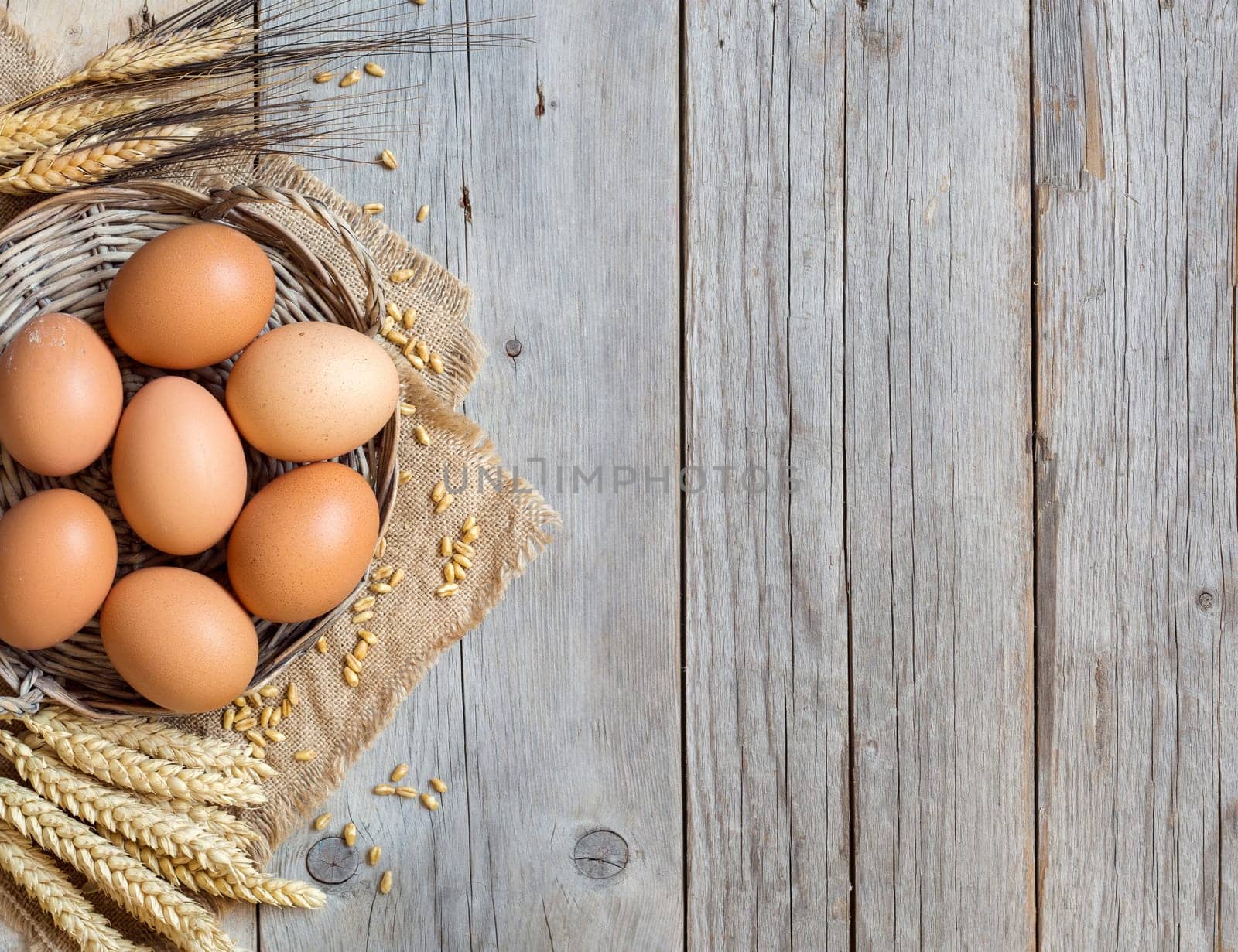 Chicken eggs and wheat on the old wood