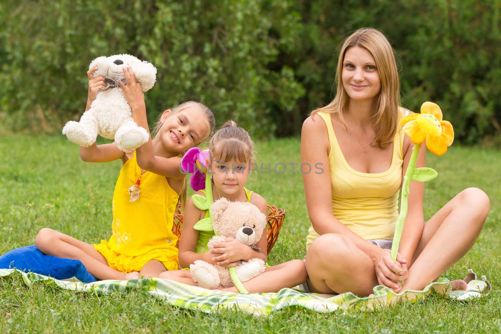 Mother and daughter sitting with soft toys on a picnic