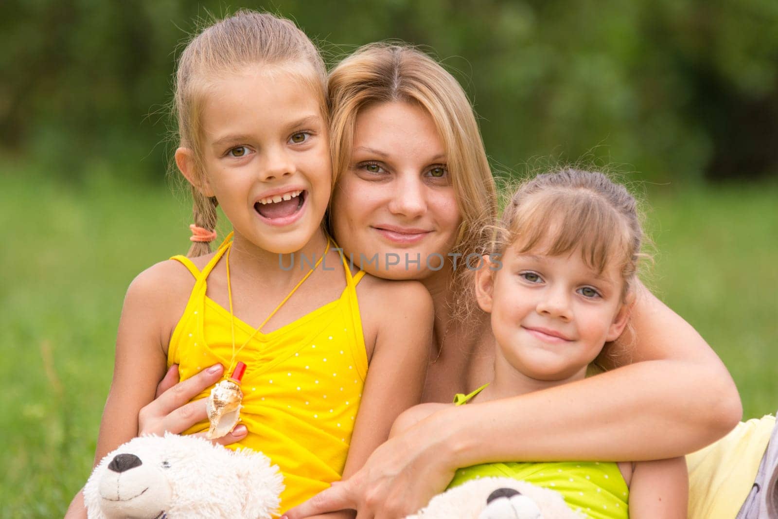 Young mother hugging her two daughters, five and seven years