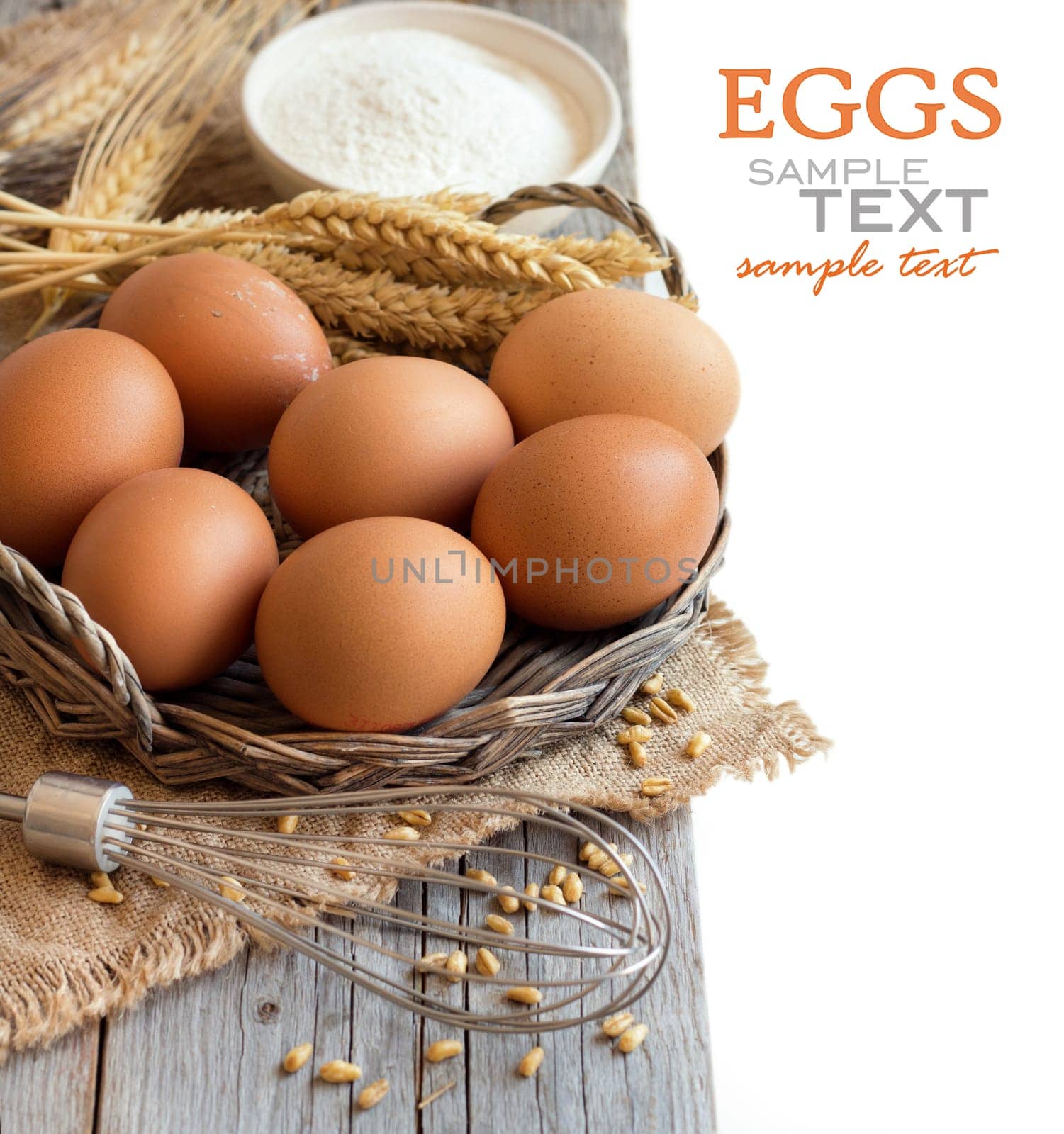 Chicken eggs, whisk, wheat and flour on the old wood