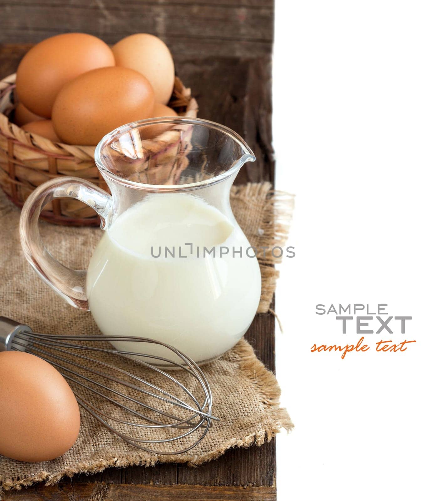 Chicken eggs, whisk and milk on the old wooden table