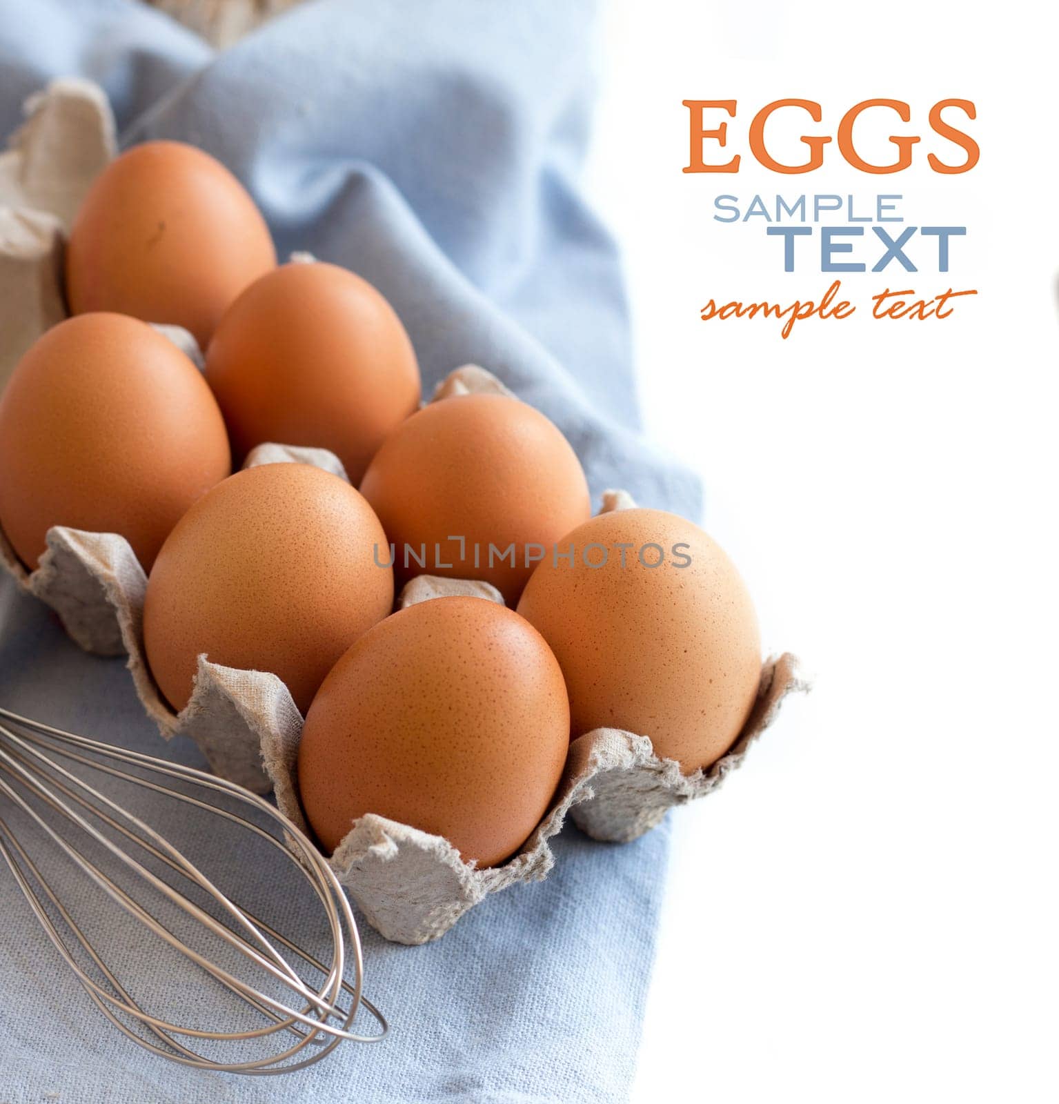 Chicken eggs in the box and whisk on the blue napkin