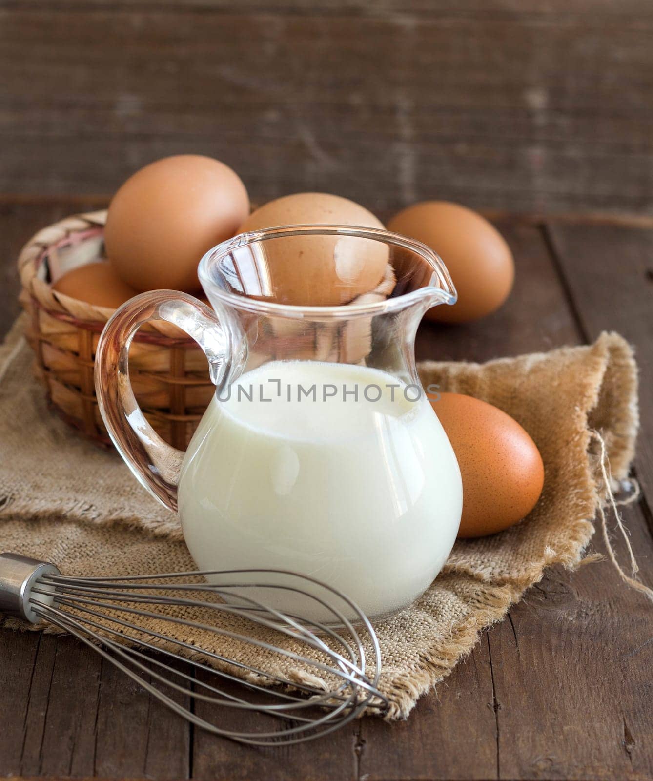 Milk, whisk and eggs on the old wooden table
