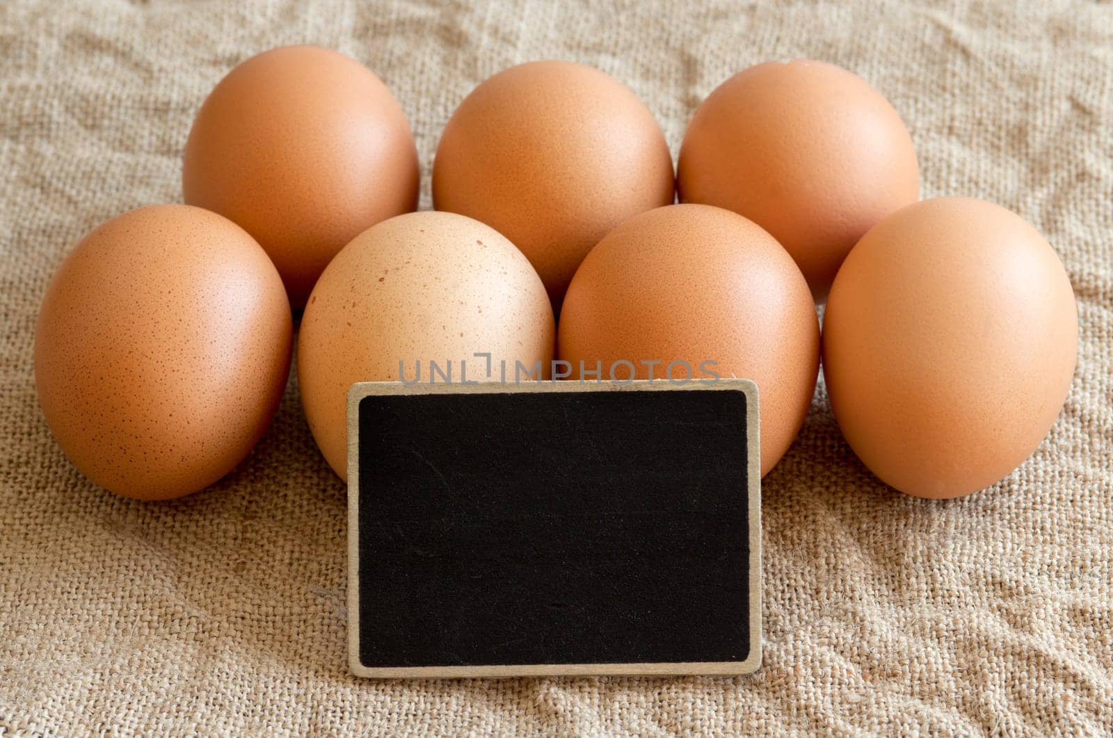 Chicken eggs and small chalkboard on burlap close up