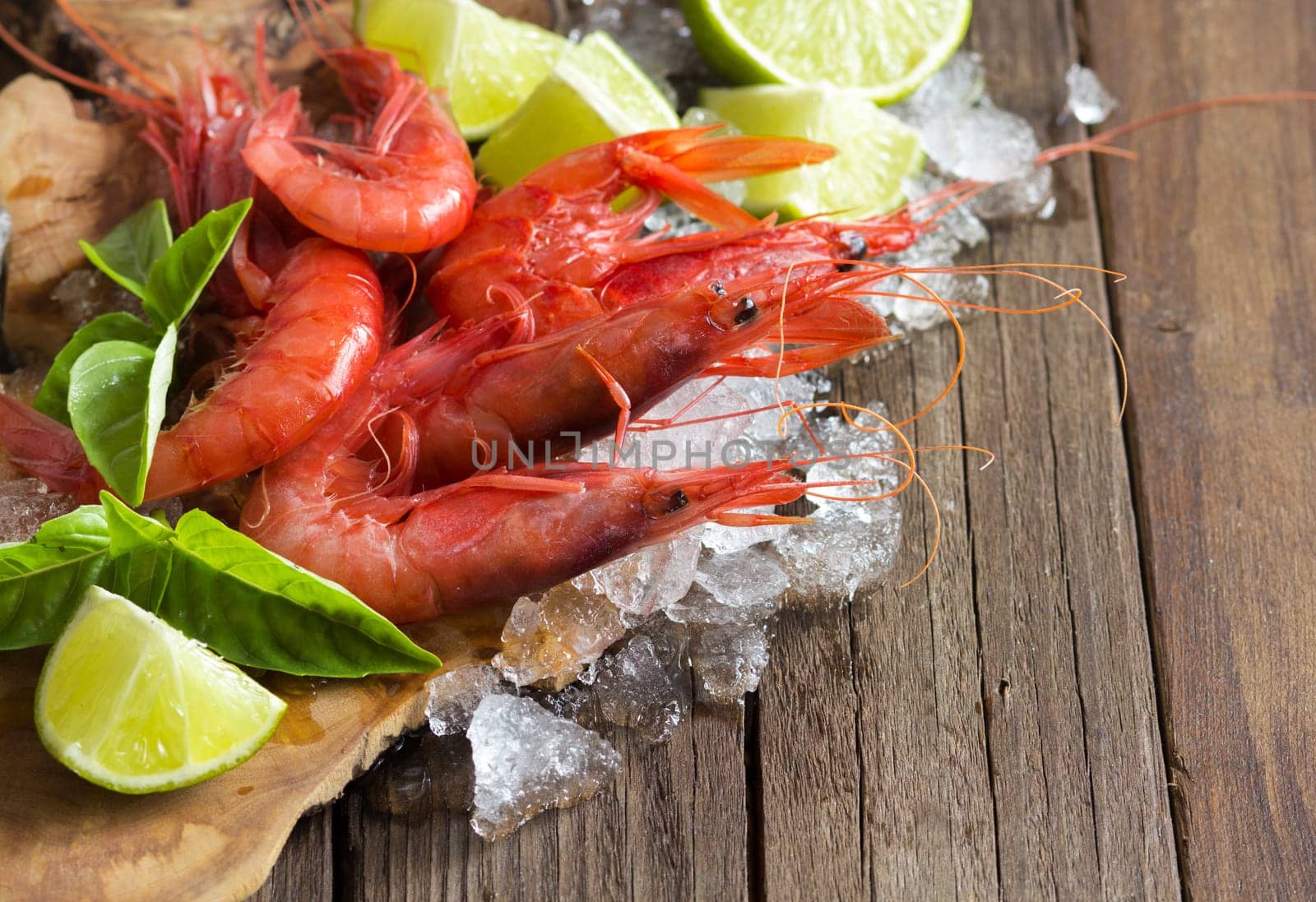 Raw shrimps with lime and basil over dark background