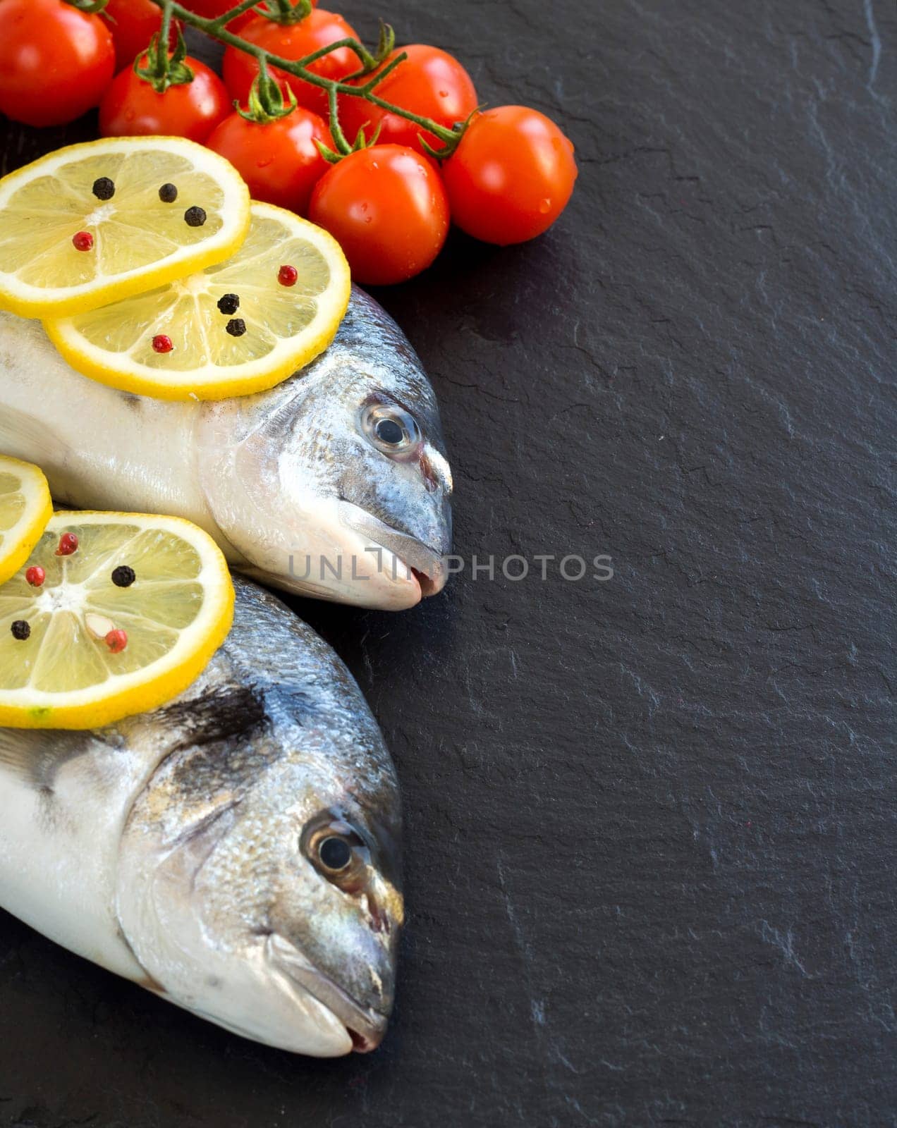 Fresh dorado fish and vegetables on dark vintage background