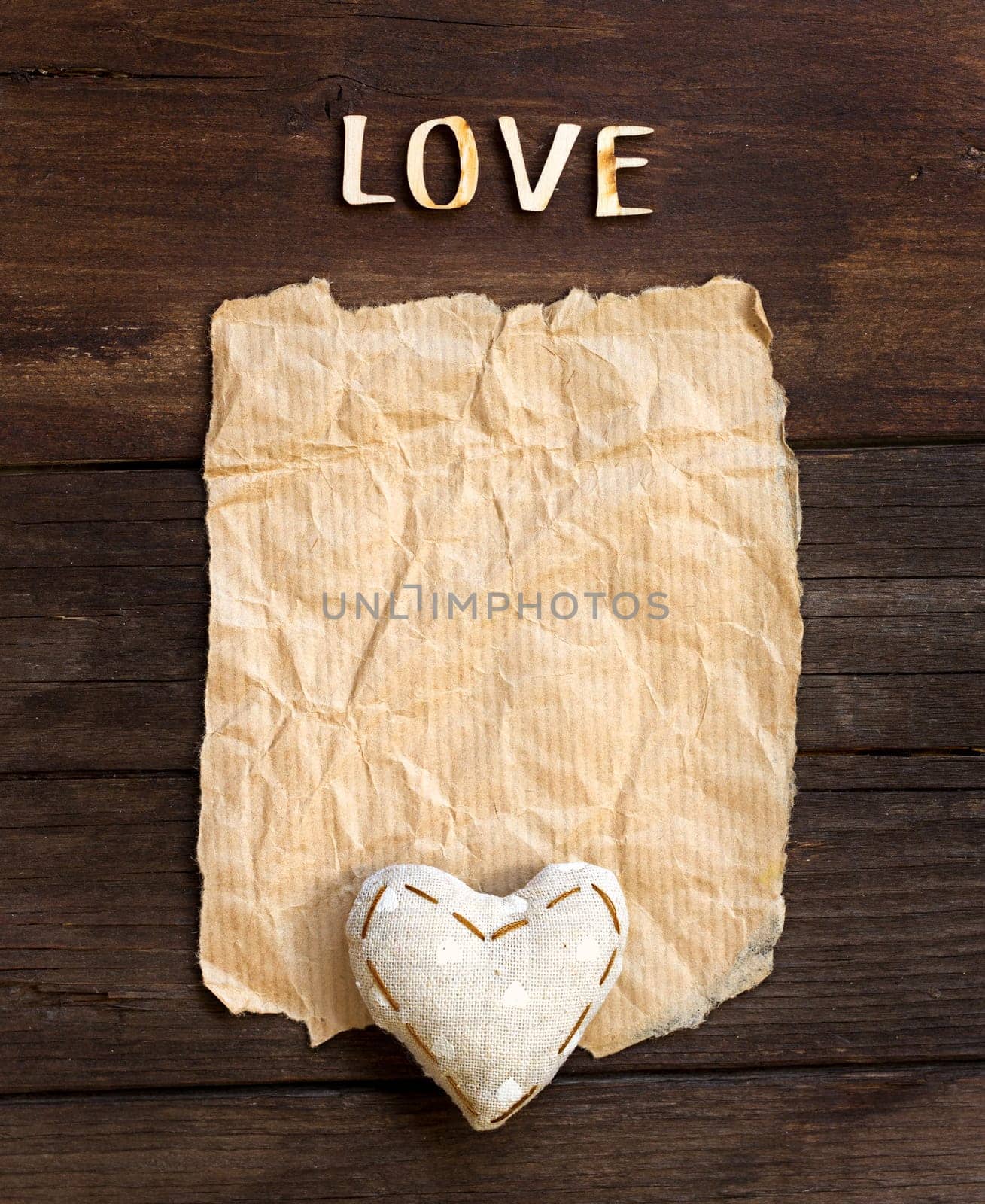 Old paper, heart and word Love on the wood background