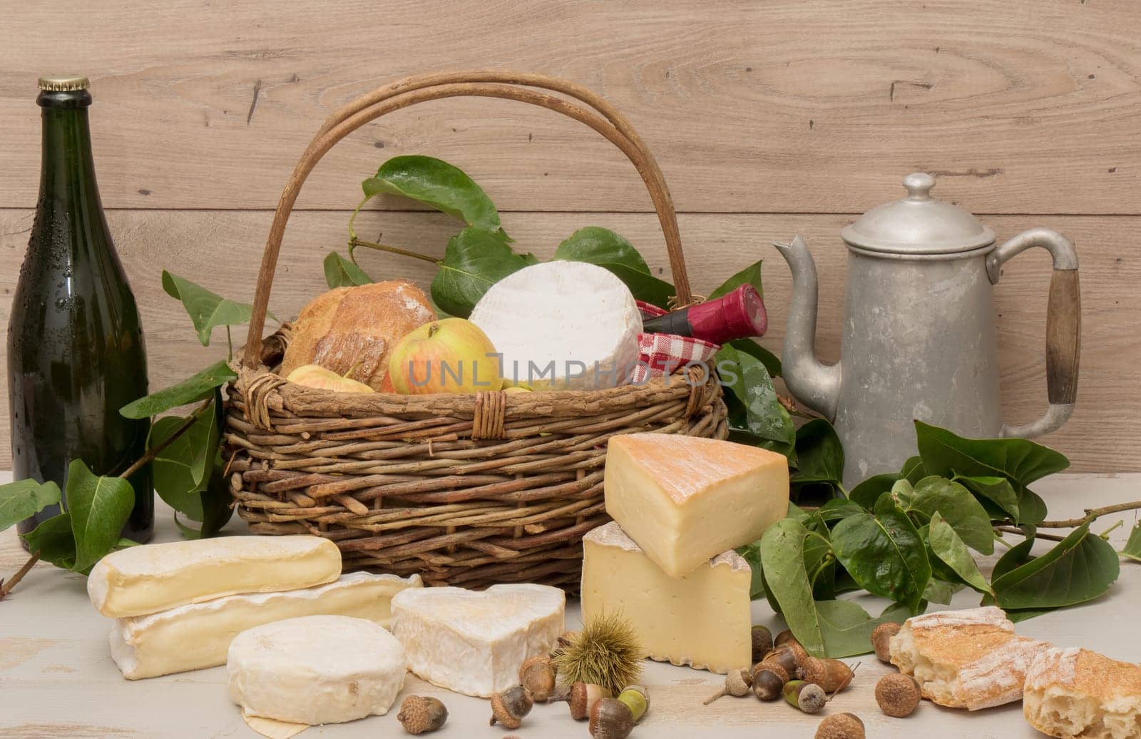several french cheeses with a bottle of cider