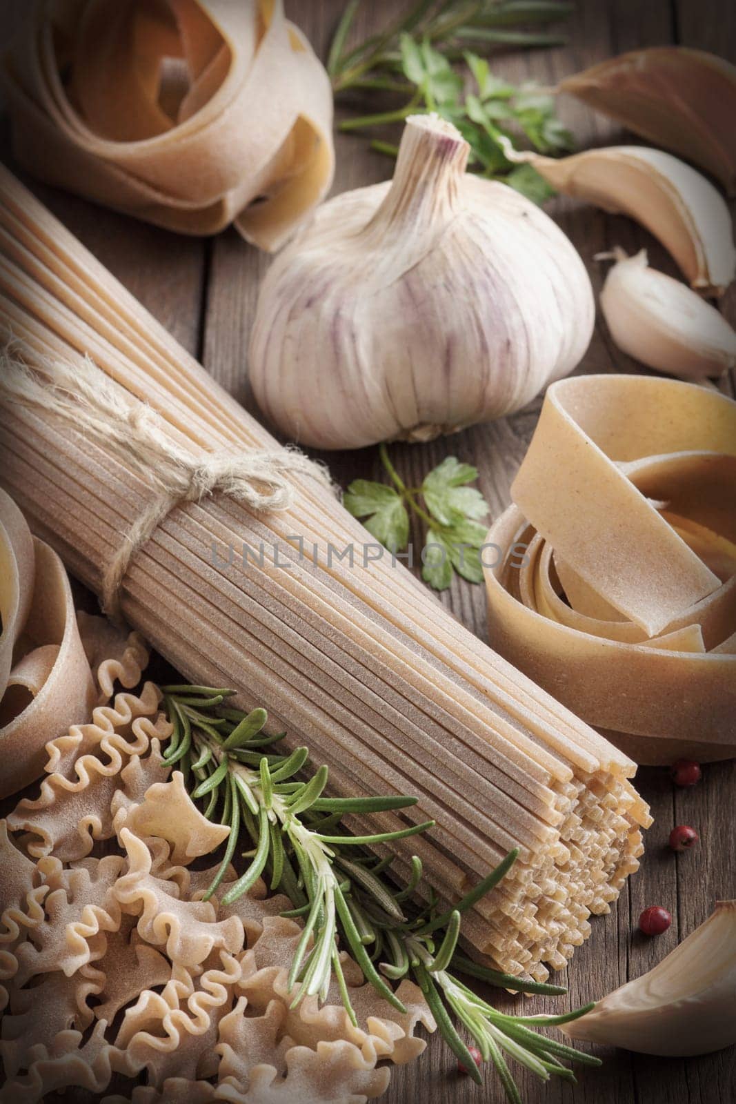Whole wheat italian pasta with garlic and herbs on wood