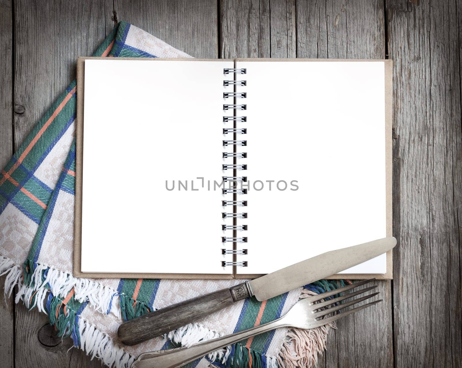 Blank cooking recipe book with fork, knife an napkin on wooden table
