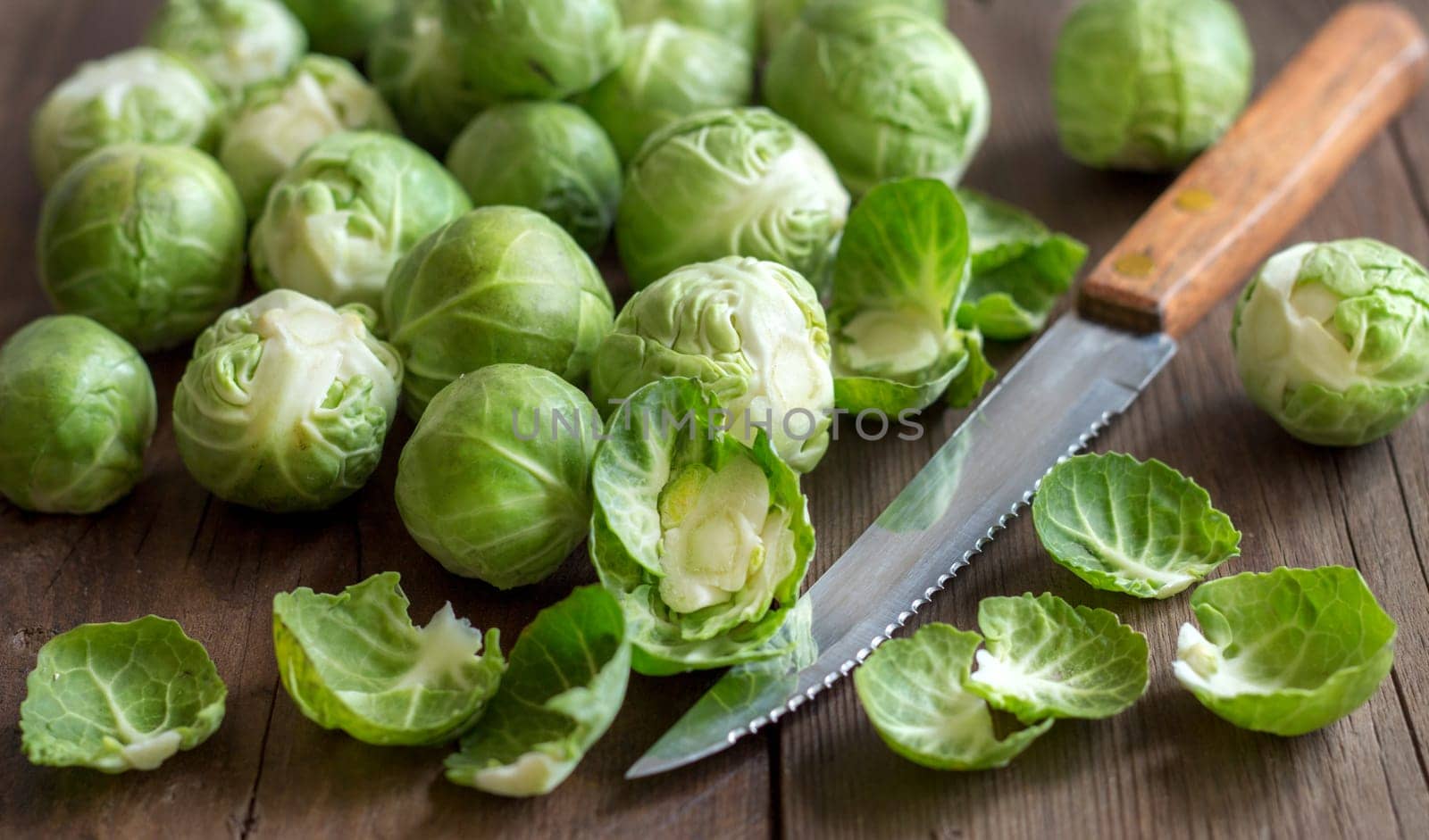 Brussels sprouts with leaves and knife on wood