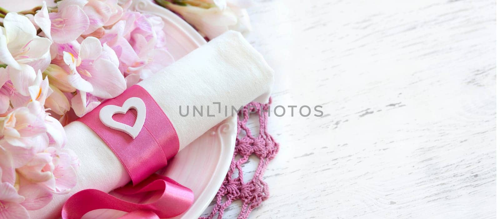 Festive wedding table setting with pink flowers and ribbon