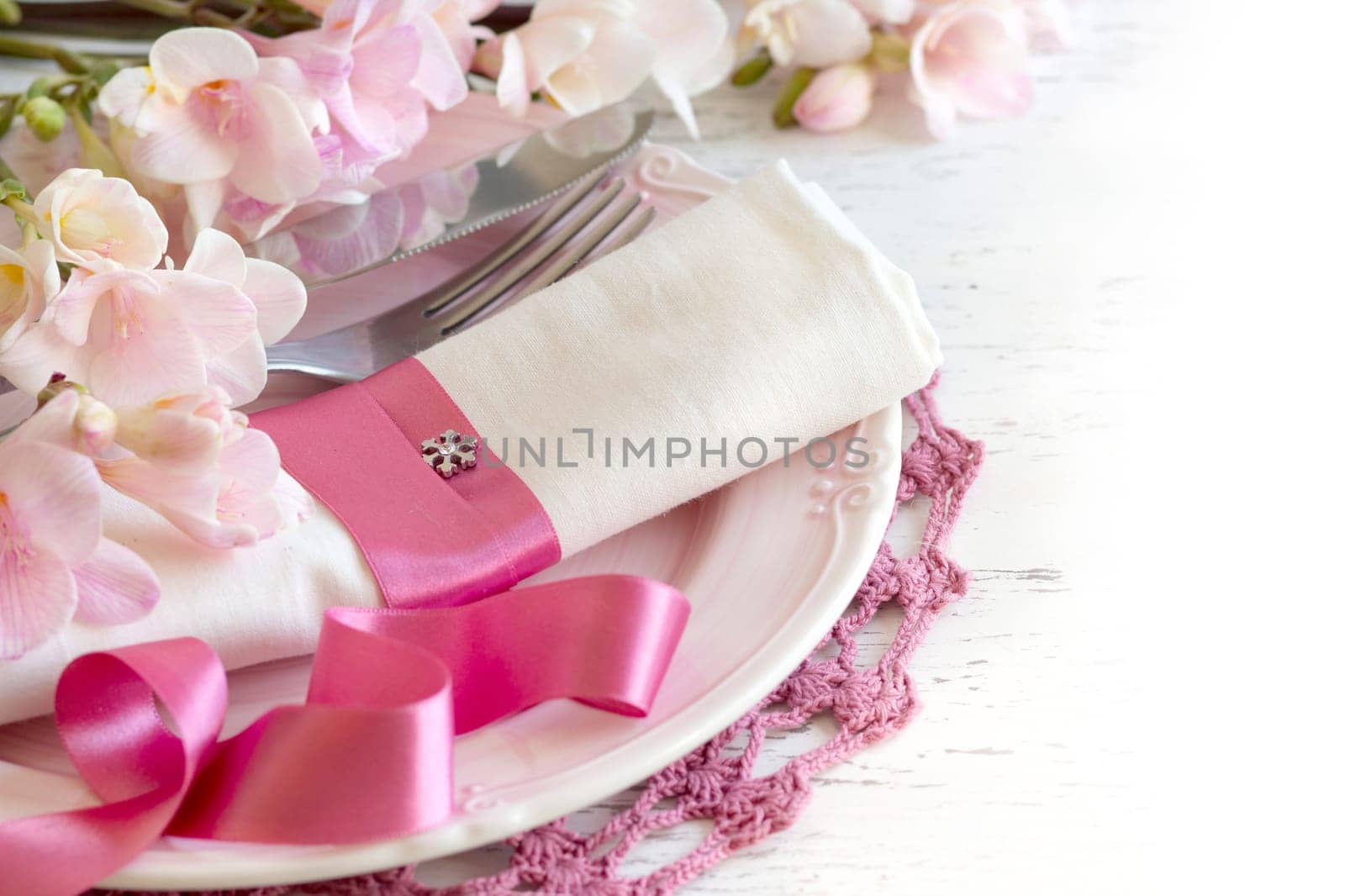Festive wedding table setting with pink flowers and ribbon