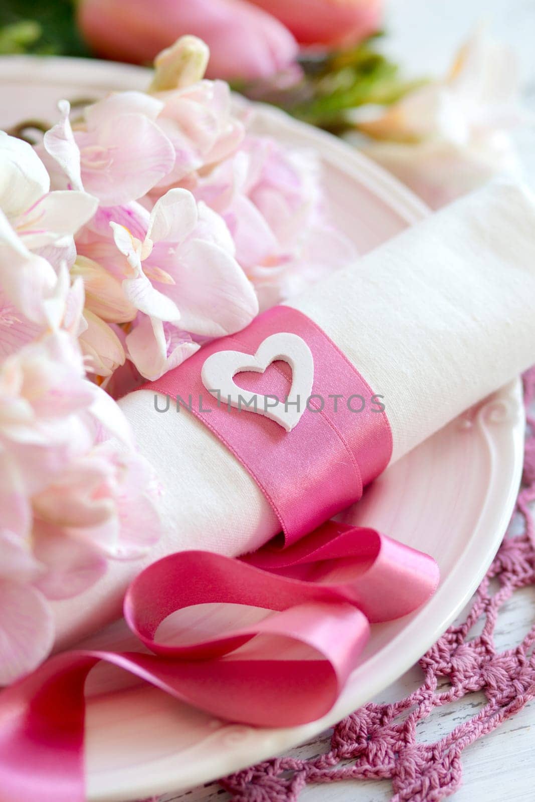 Festive wedding table setting with pink flowers and ribbon